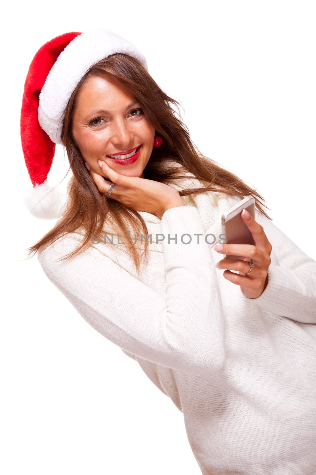 Attractive woman with red Santa hat reads a text message on her phone smartphone and sends Christmas wishes smiling with joy isolated on white with text-free free-space