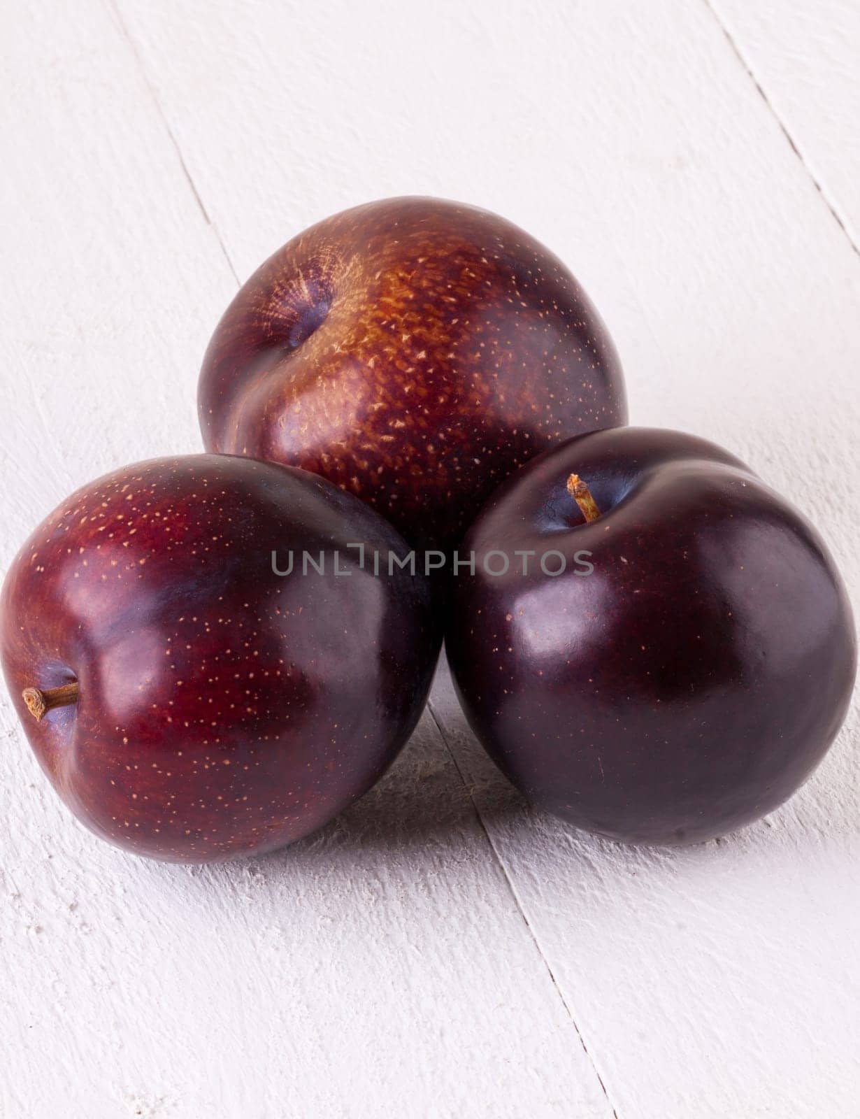 Fresh shiny juicy plums with ripe color with stem up as close-up