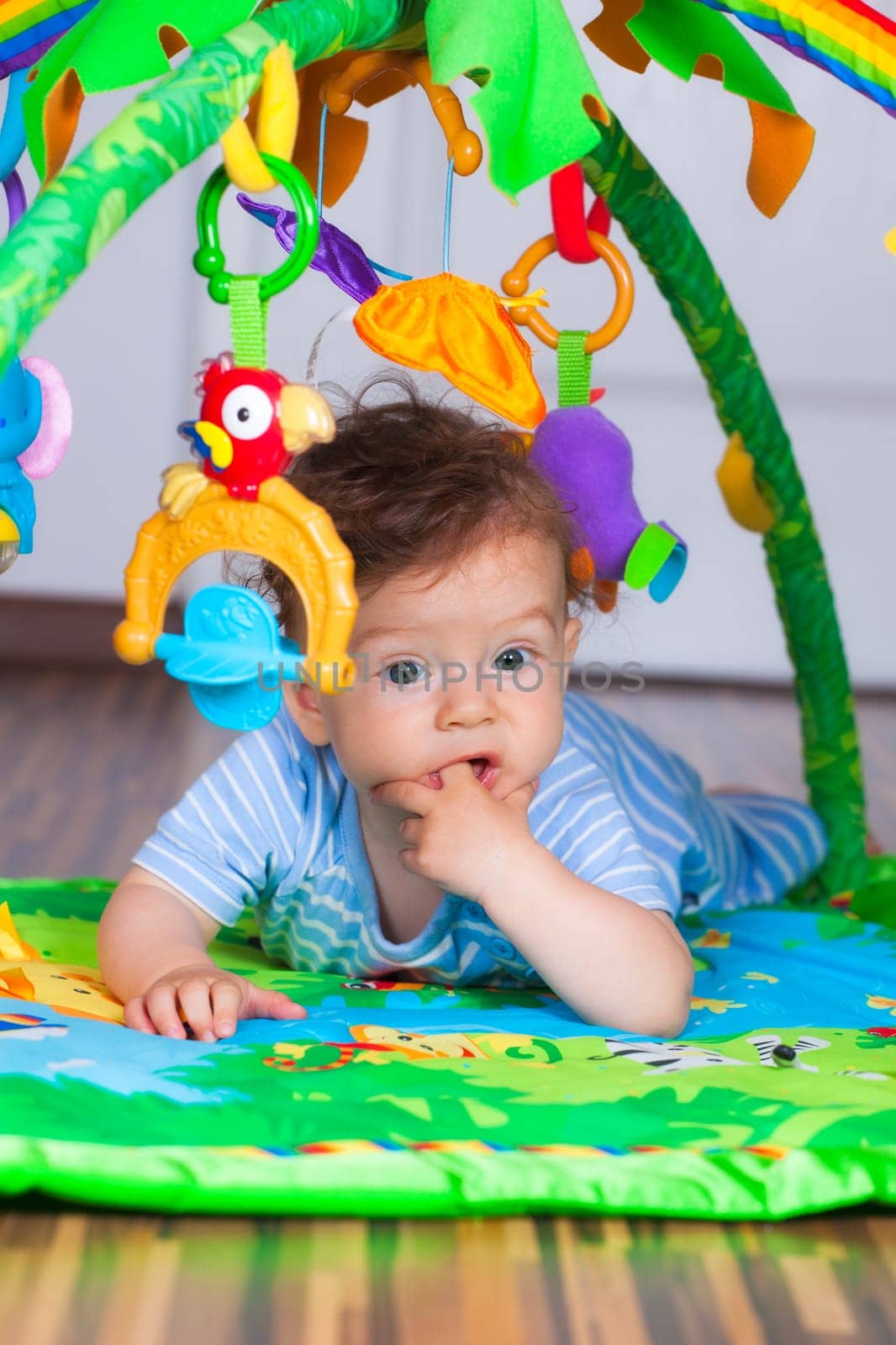 Portrait of a happy 6 months old baby boy at tummy time on the play gym.