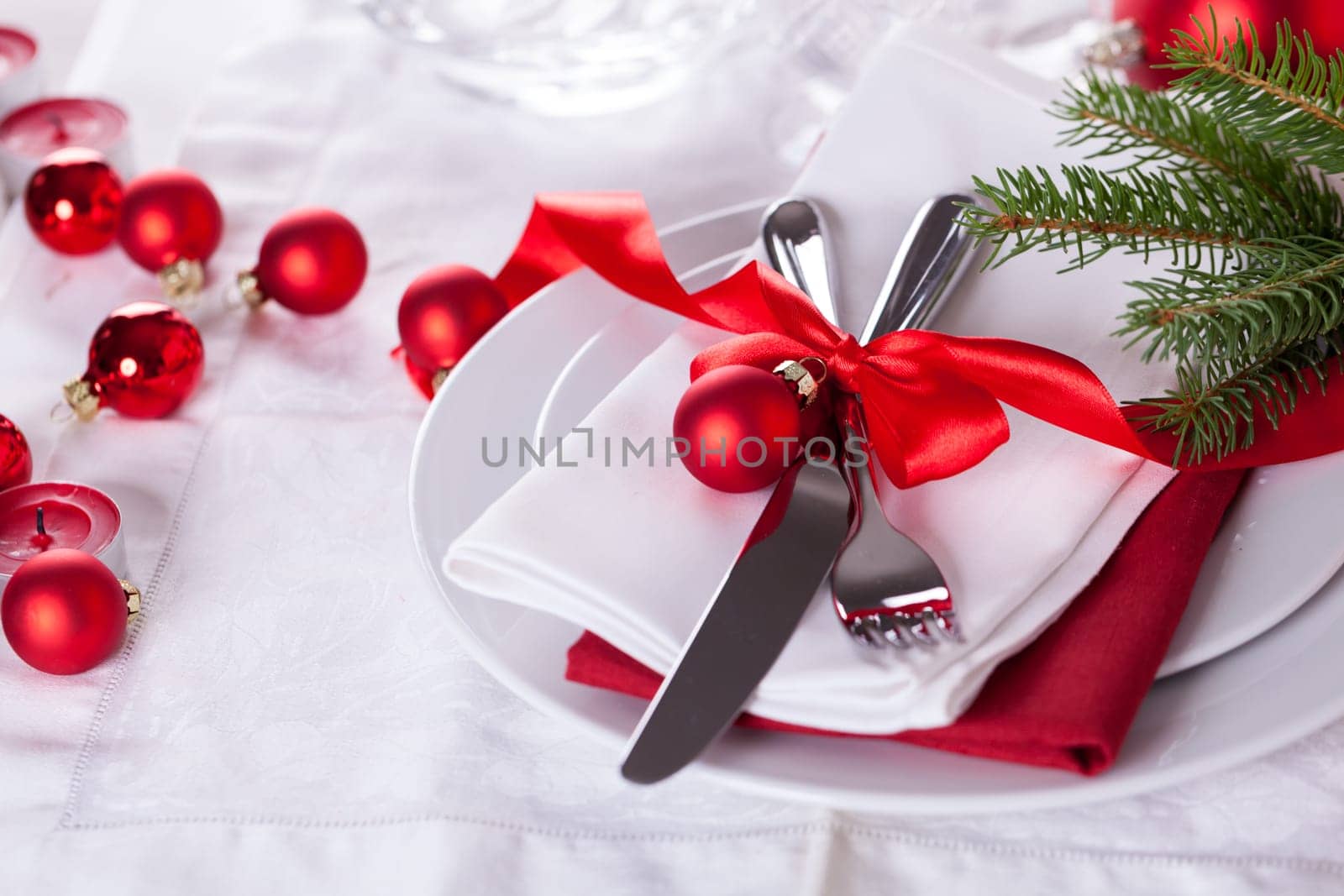 Romantic Christmas table with red balls and red bow with cutlery knife and fork on a napkin