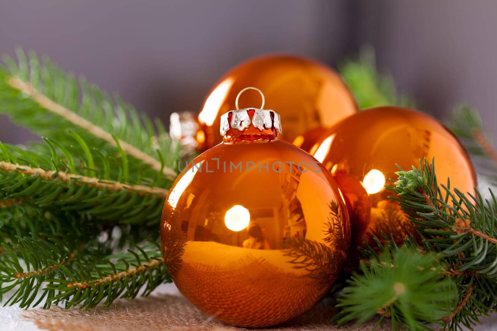 Shiny orange glass balls Christmas balls with green twigs on a jute sack as a close-up
