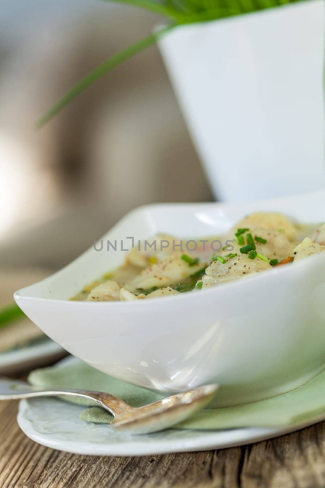 Bowl with Russian Pelmeni Italian tortellini with broth and parsley close-up on a wooden table