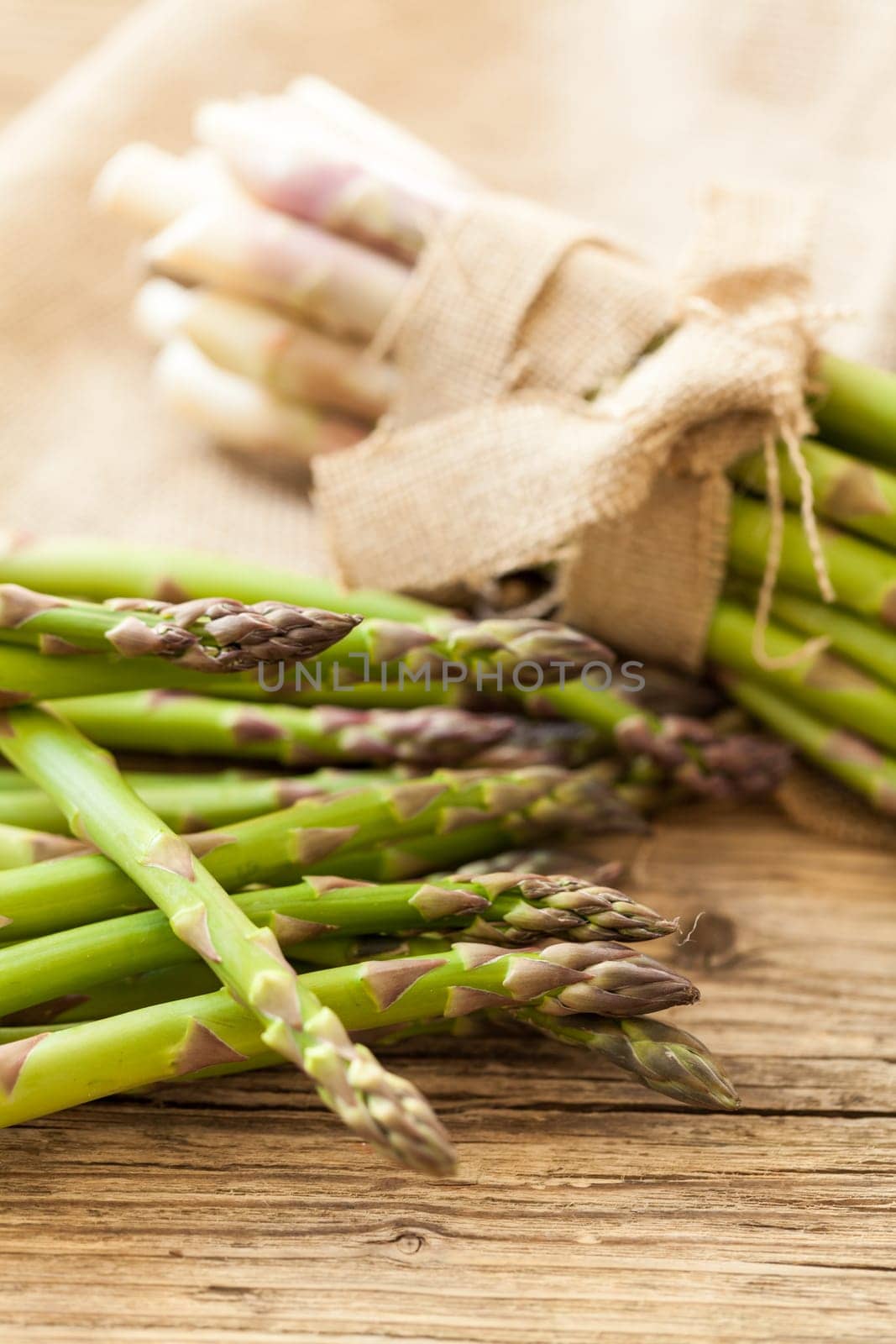 Fresh healthy green asparagus as a close-up on a wooden table in sunlight