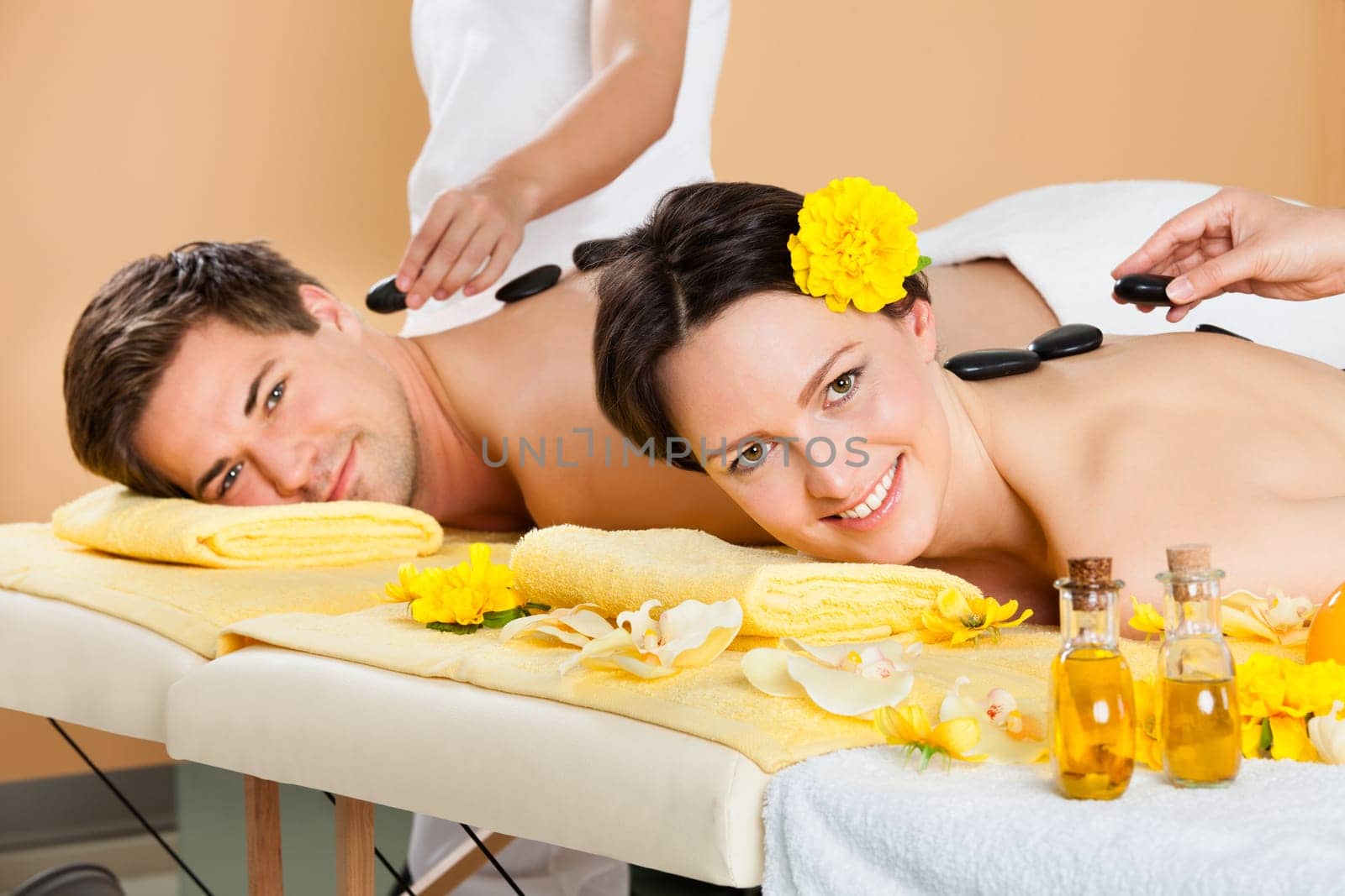 Relaxed young couple receiving hot stone therapy at beauty spa