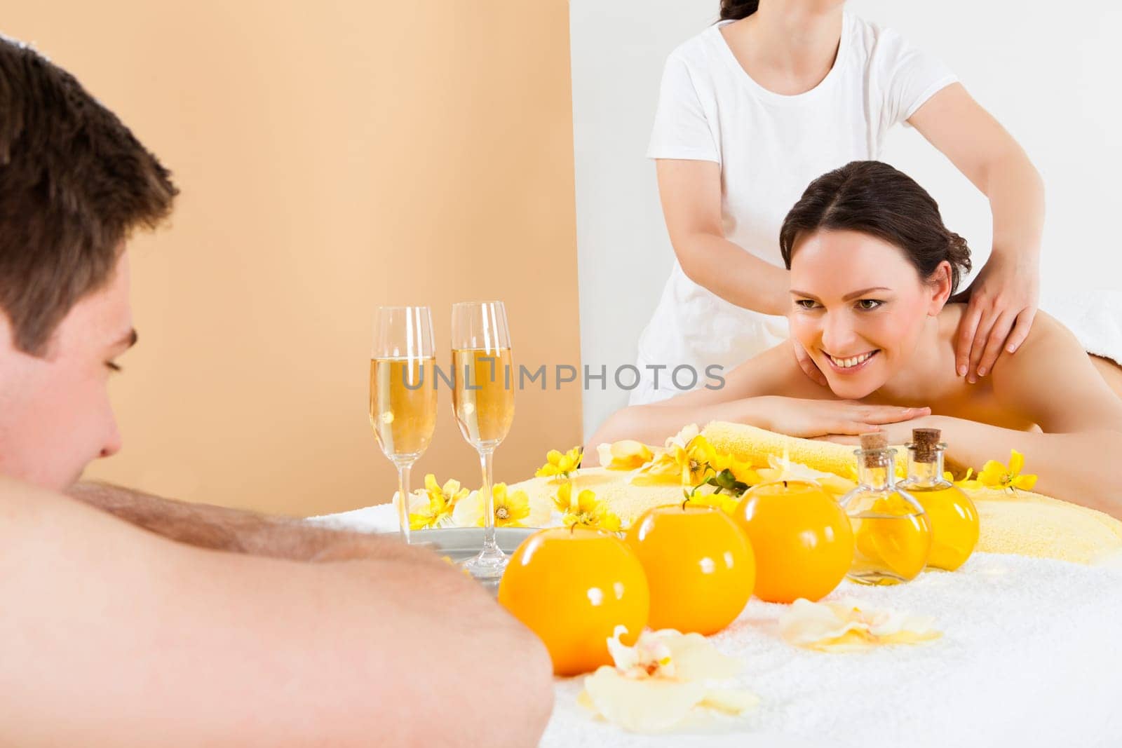 Happy woman looking at man while receiving shoulder massage in beauty spa