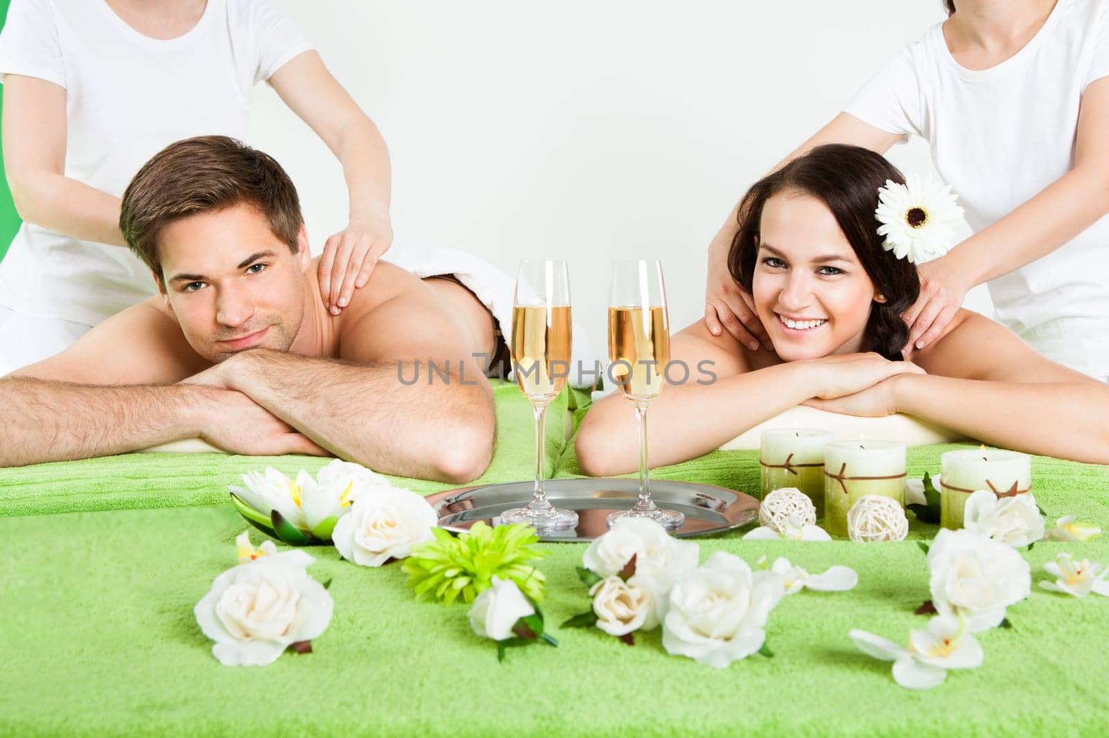 Portrait of happy young couple receiving shoulder massage at beauty spa