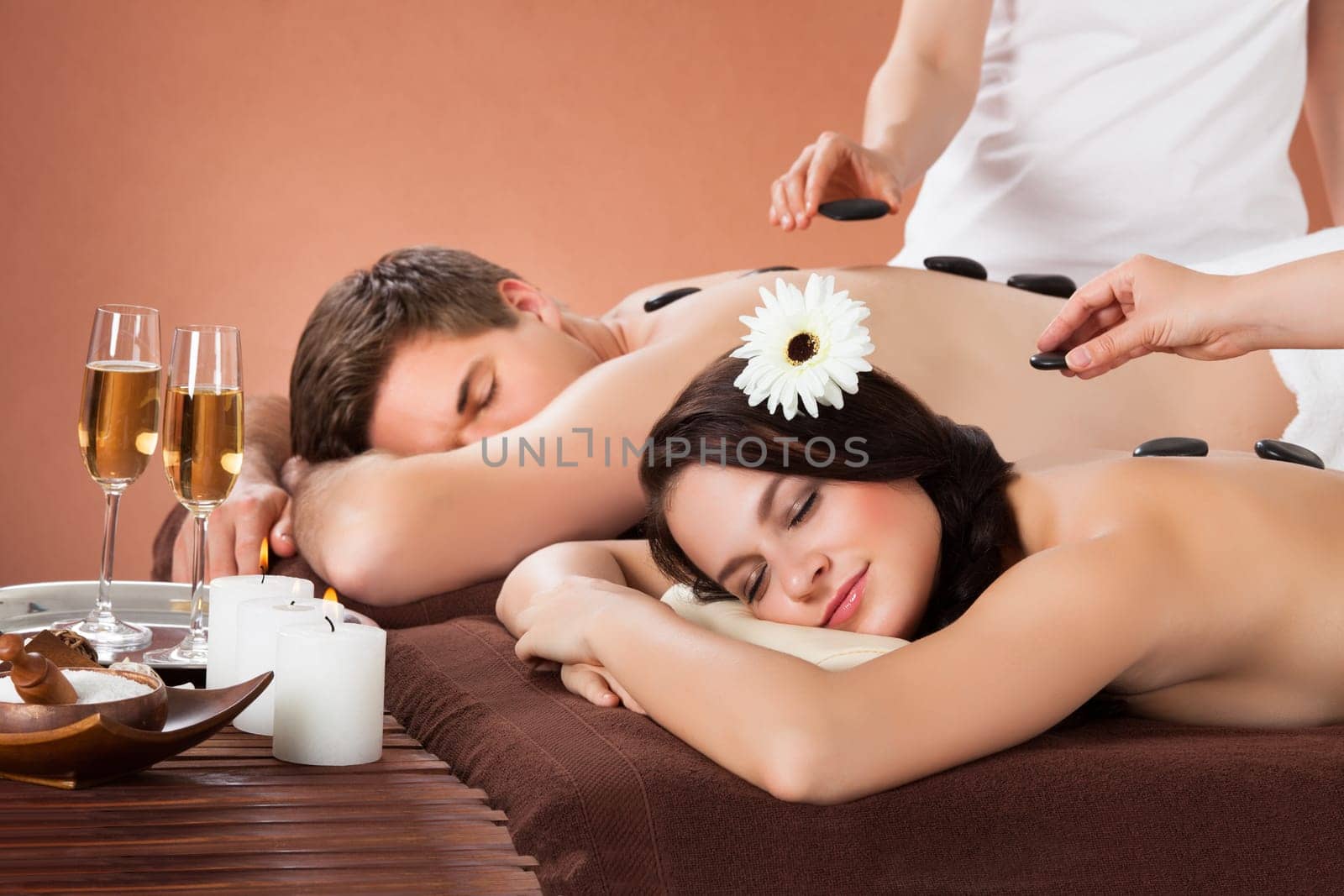 Relaxed young couple receiving hot stone therapy at beauty spa