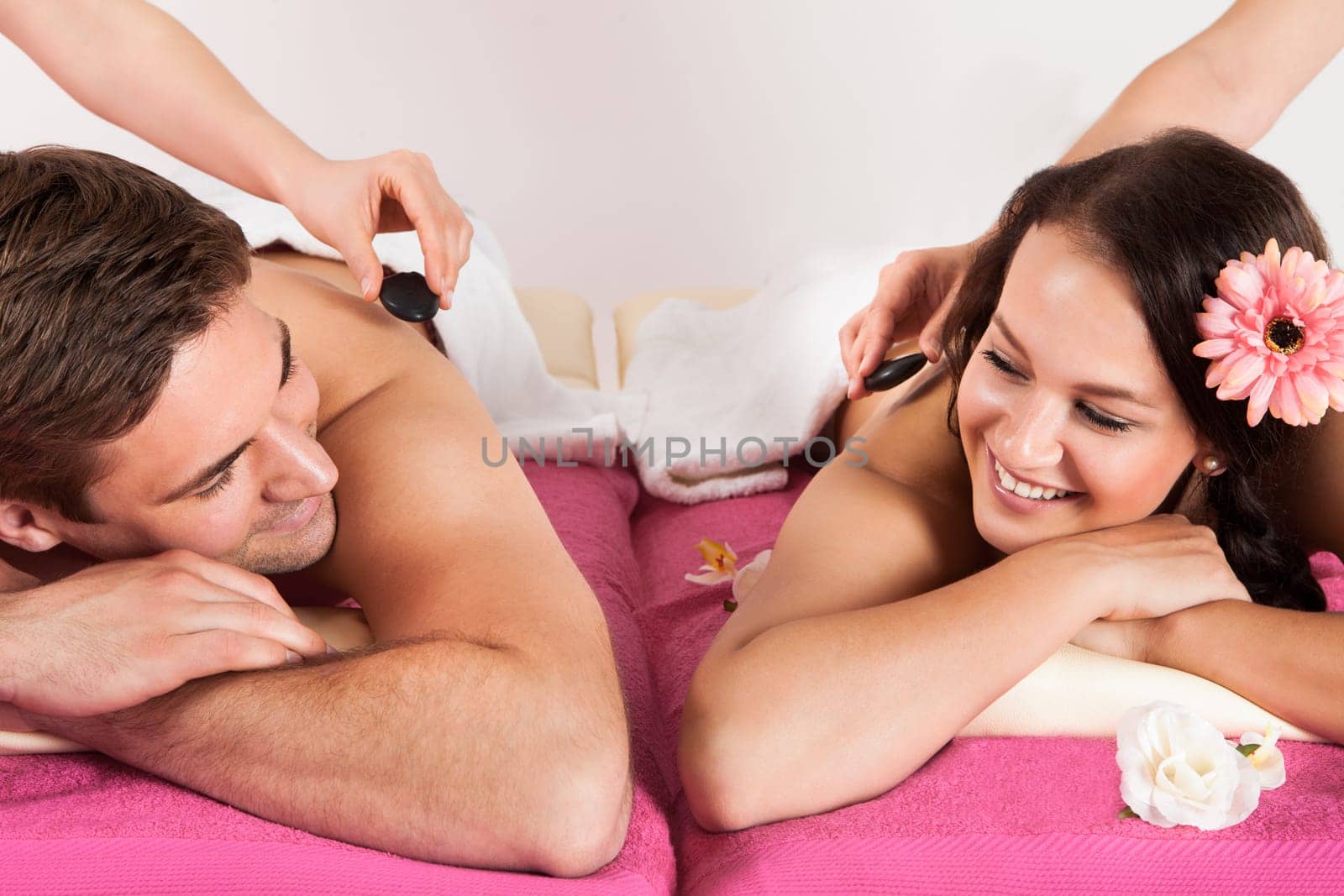 Portrait of happy young couple enjoying hot stone massage at beauty spa