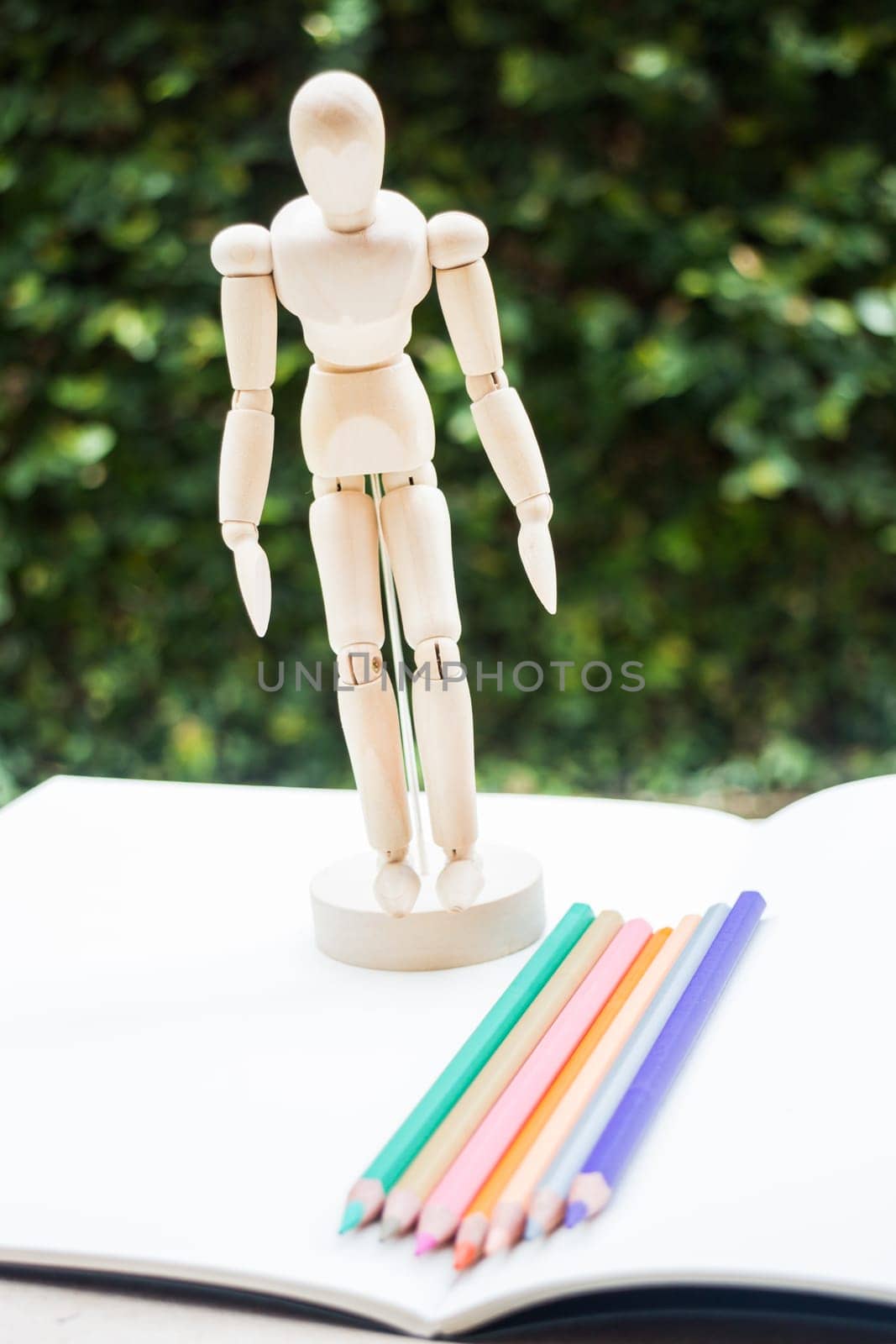Wood mannequin standing on artist drawing paperbook