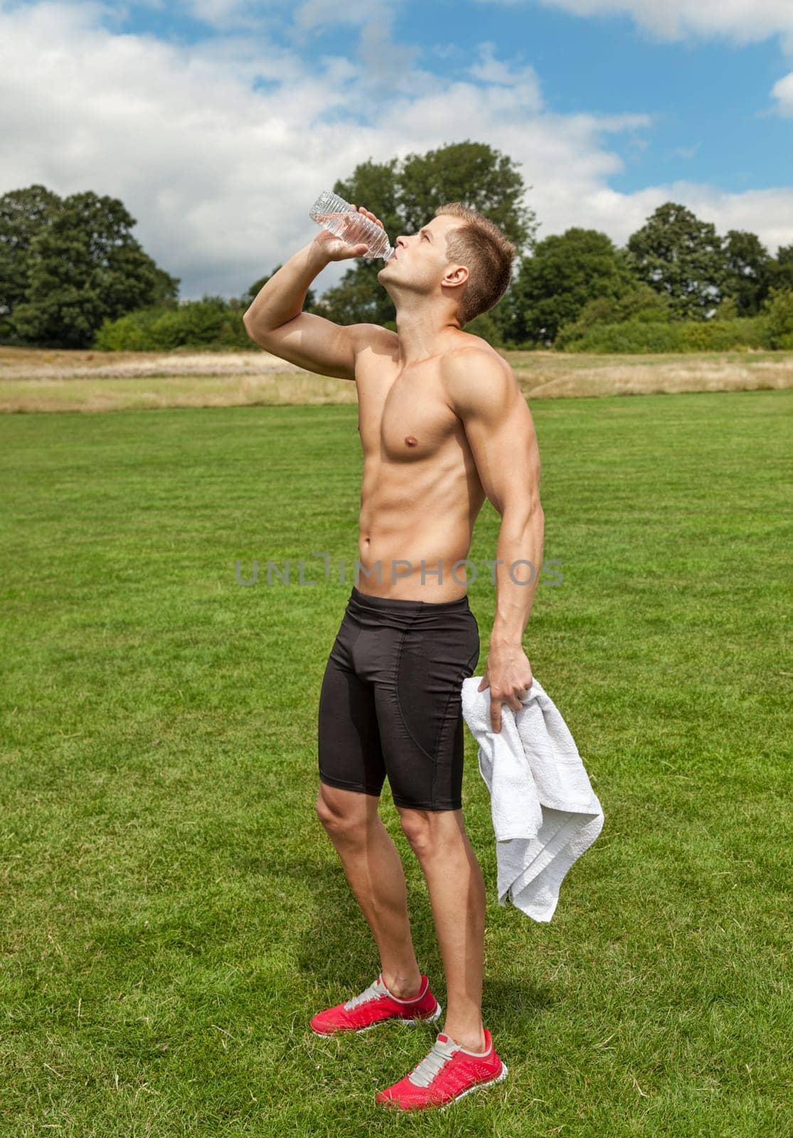 Muscular young man drinking water after excercise