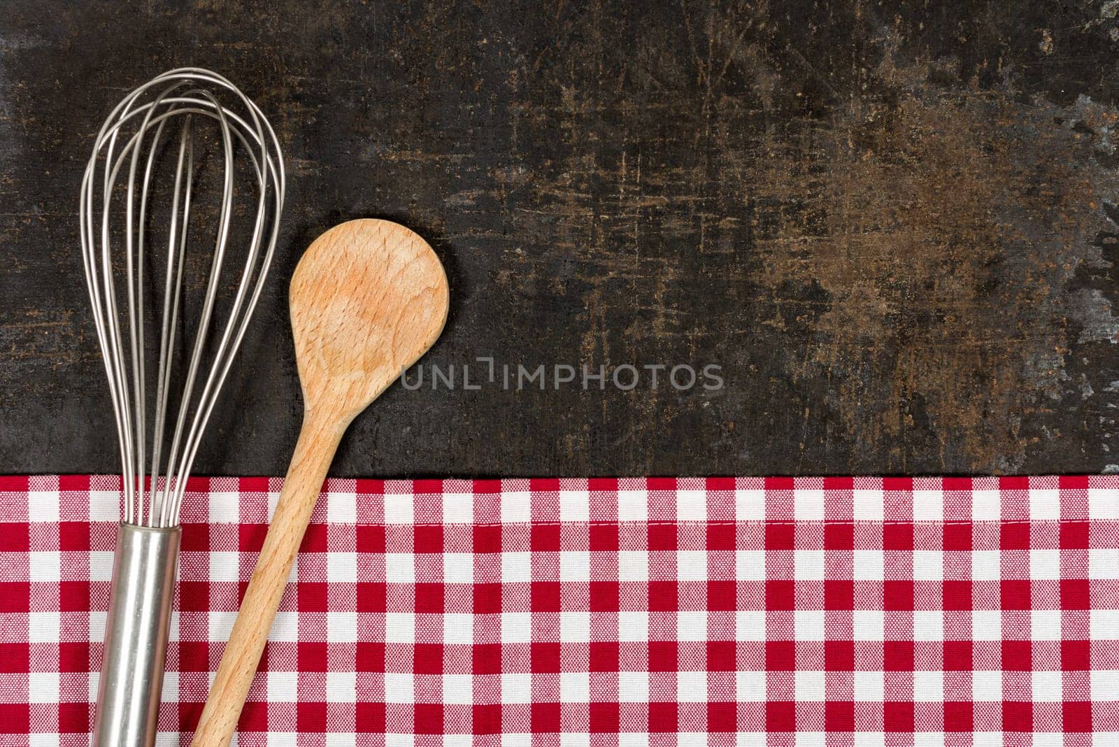 Old baking tray with red checkered tablecloth and baking utensils