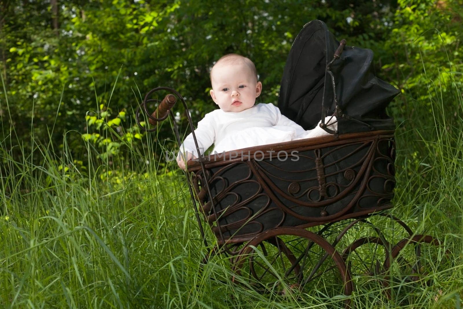 Baby girl is sitting in a vintage pram