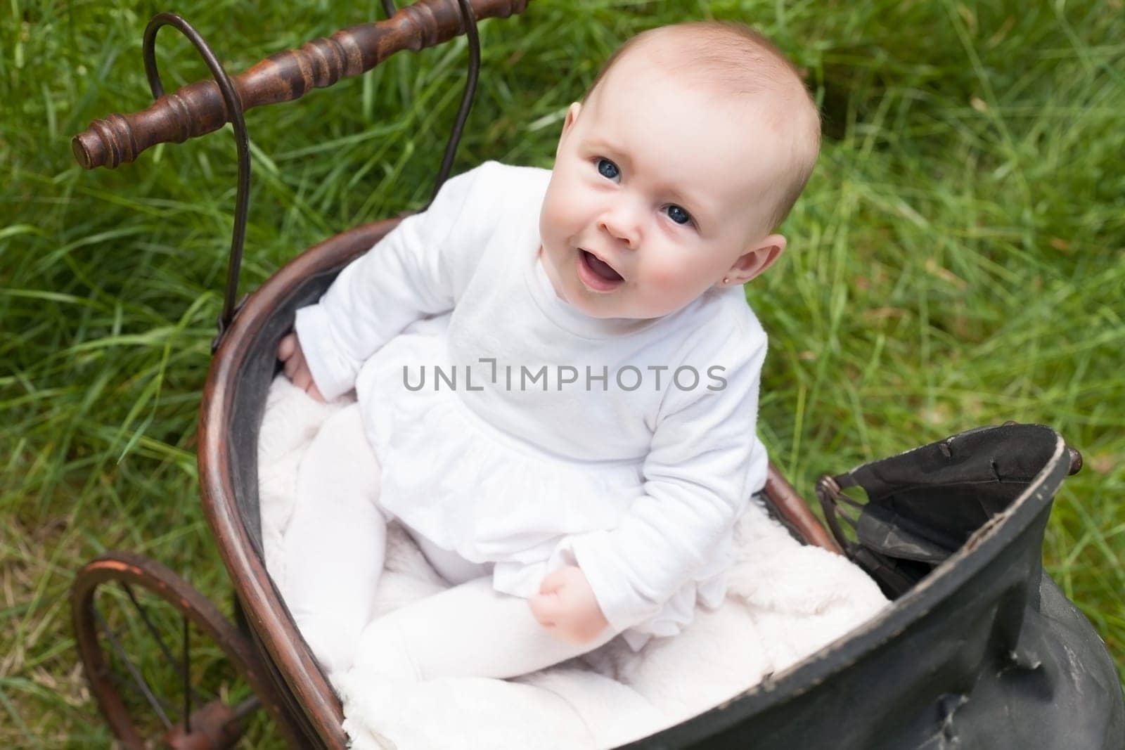 Baby girl is sitting in a vintage pram