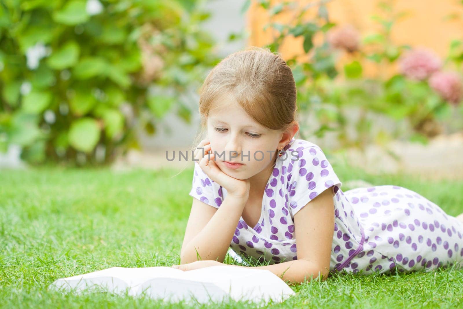 Girl reading a book in the park laid down on the grass