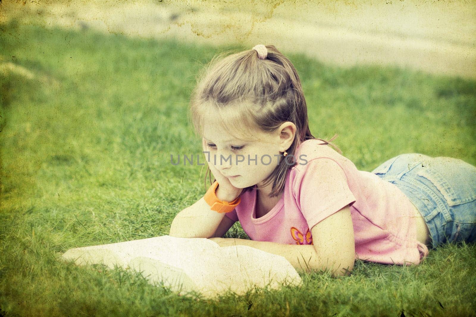 Girl reading a book in the park laid down on the grass