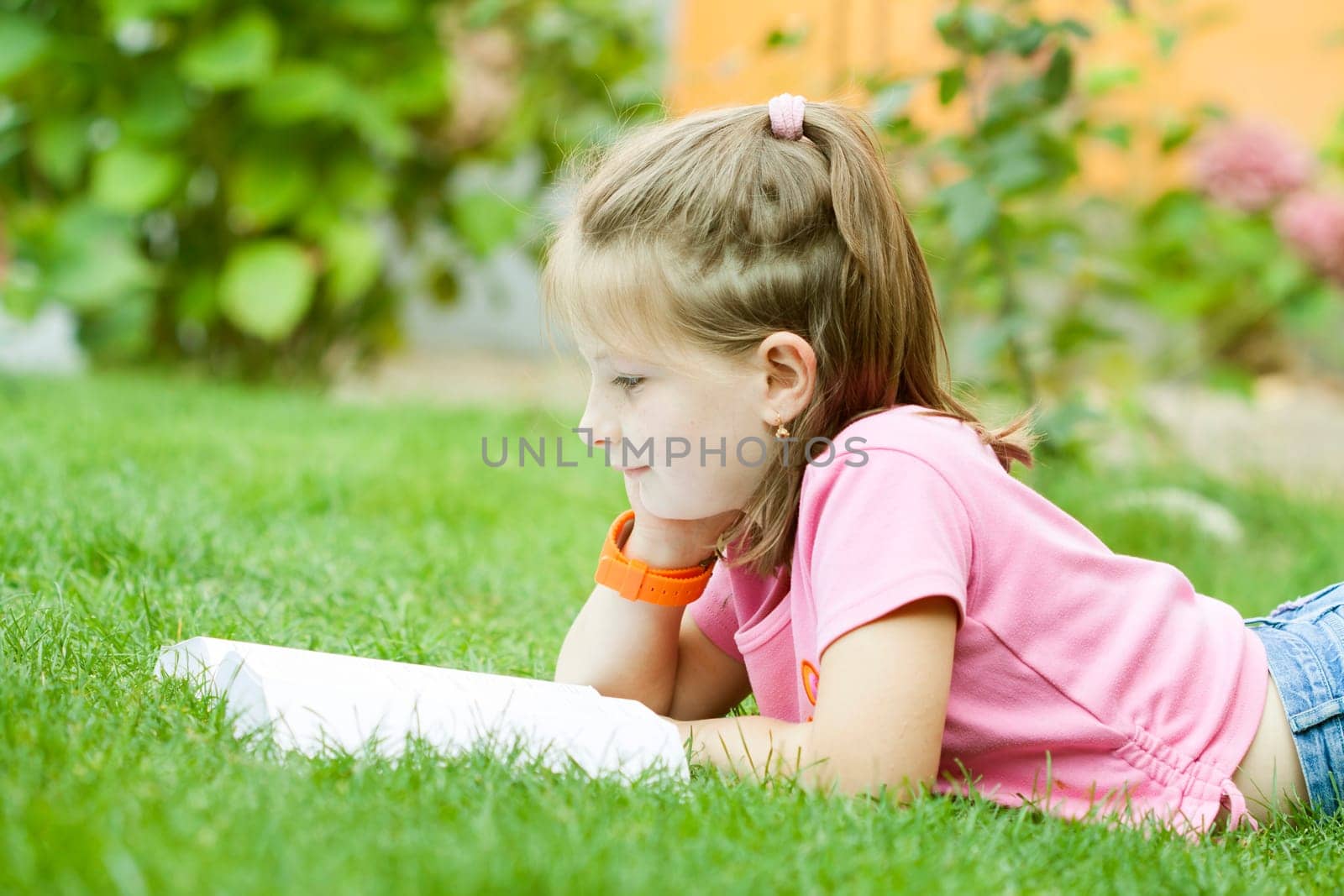 Girl reading a book in the park laid down on the grass