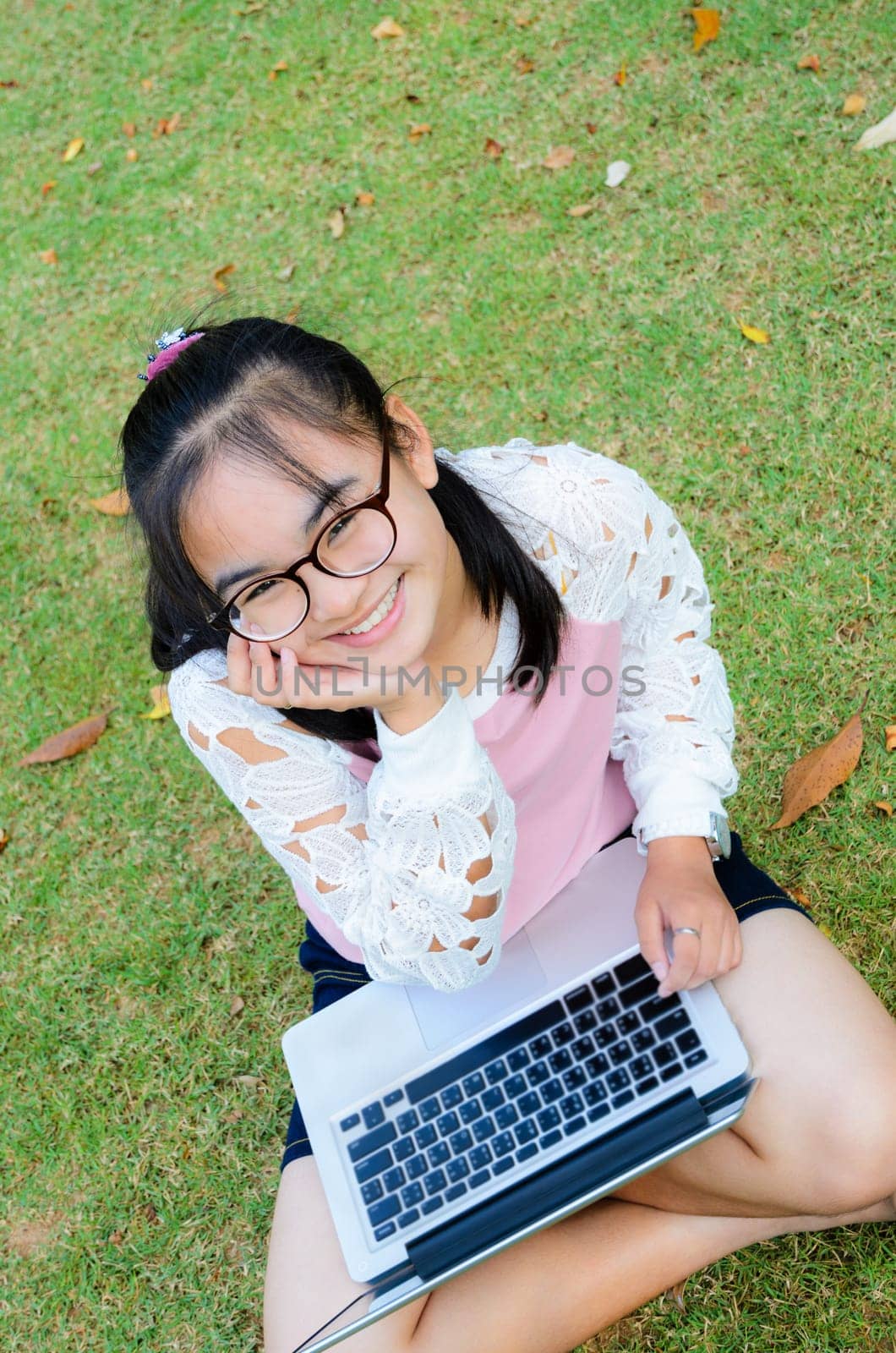 Lovely girl is happy with a laptop on lawn in park