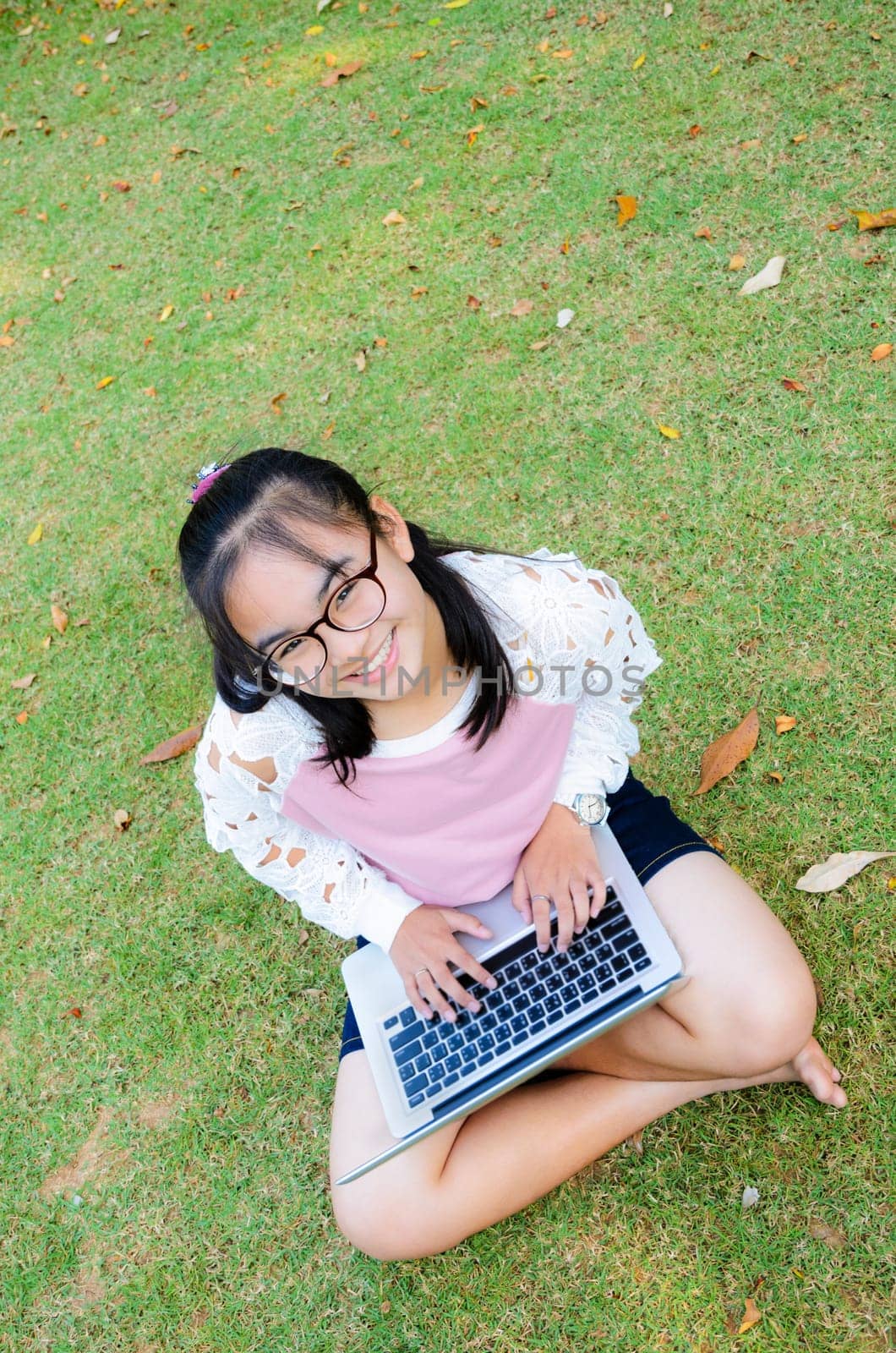 Lovely girl is happy with a laptop on lawn in park