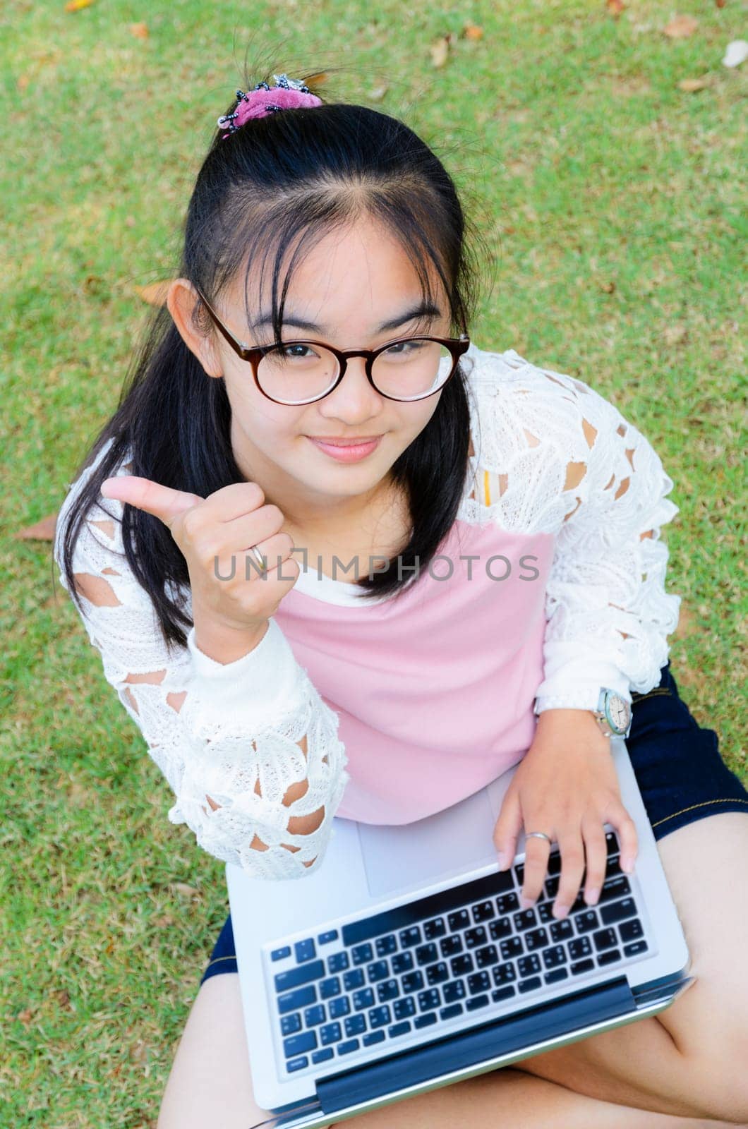 Lovely girl is happy with a laptop on lawn in park