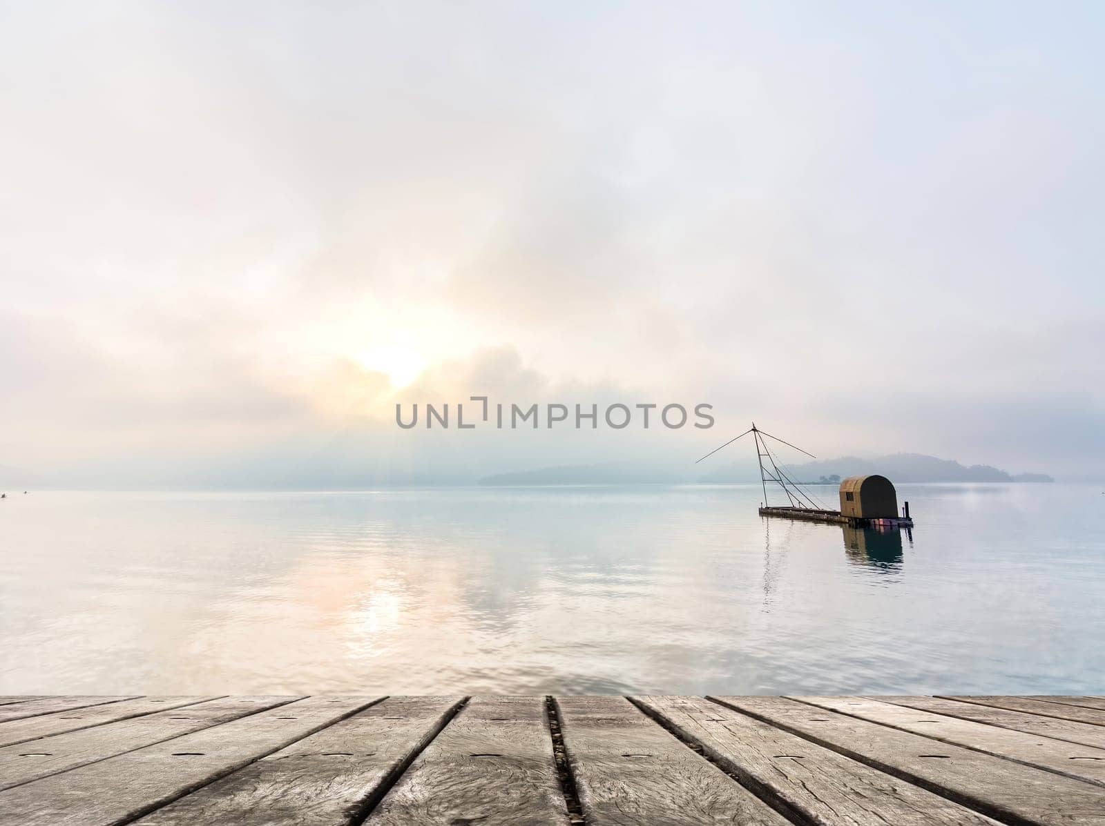 Morning concept with boat on lake with sunlight and dramatic sky, focus on wooden desk.