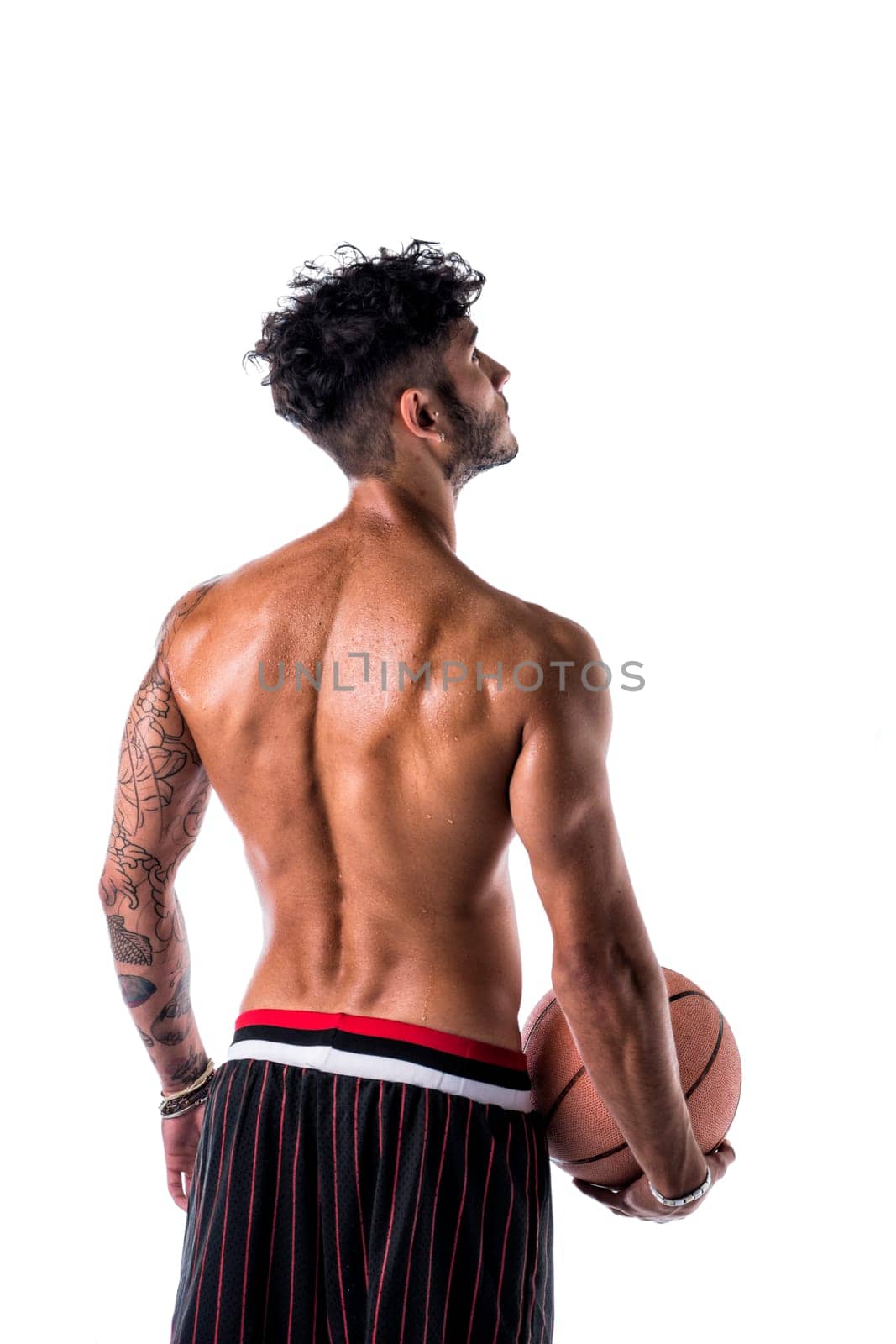 Young athletic man isolated on white background holding basketball ball, back side view