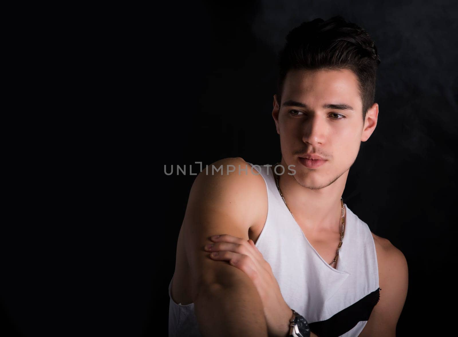 Handsome black haired young man on dark background, looking to a side