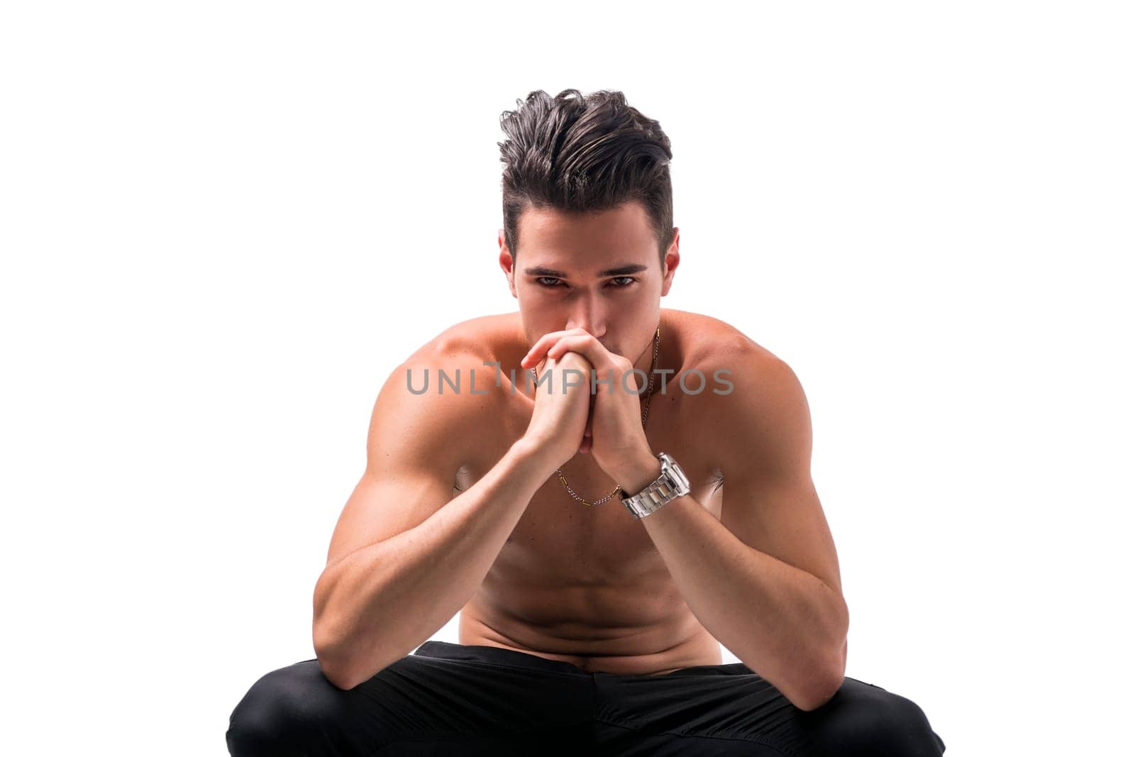 Shirtless man sitting deep in contemplation with his head to his hands staring straight ahead in a reverie, isolated on white