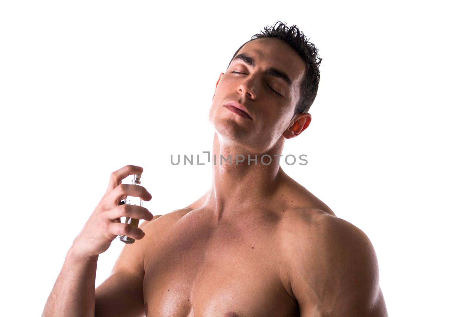 Shirtless male model spraying cologne on white background, eyes closed