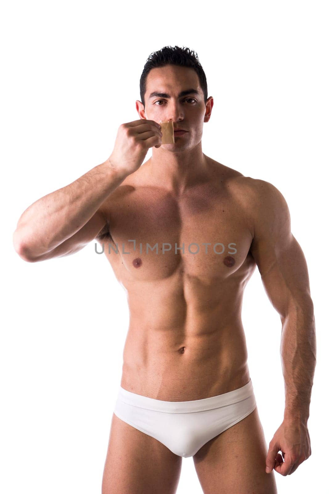 Muscular man in his underwear removing tape from his mouth on white background