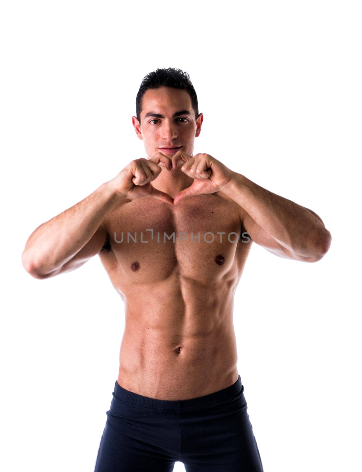 Shirtless muscular man making heart symbol with his hands on white background