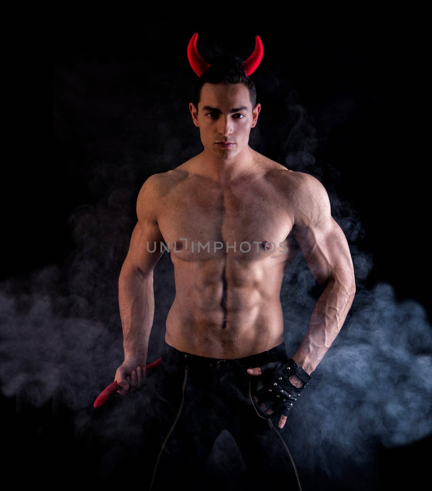 Sexy Handsome Man Wearing Devilish Horn Accessories Showing Muscled Body. Isolated on Smoky Background.