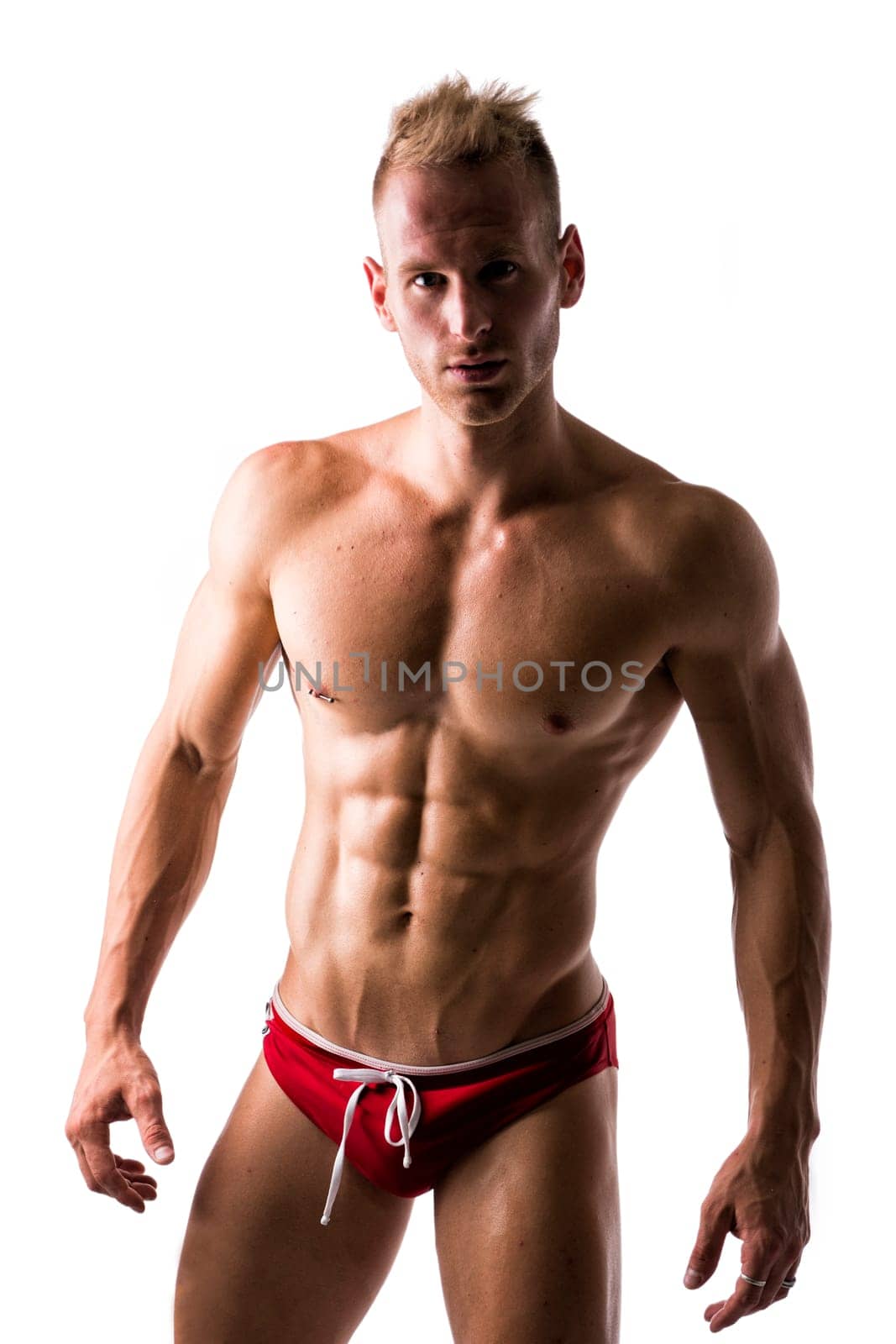 Male swimmer standing with confidence showing off his muscular physique on white background
