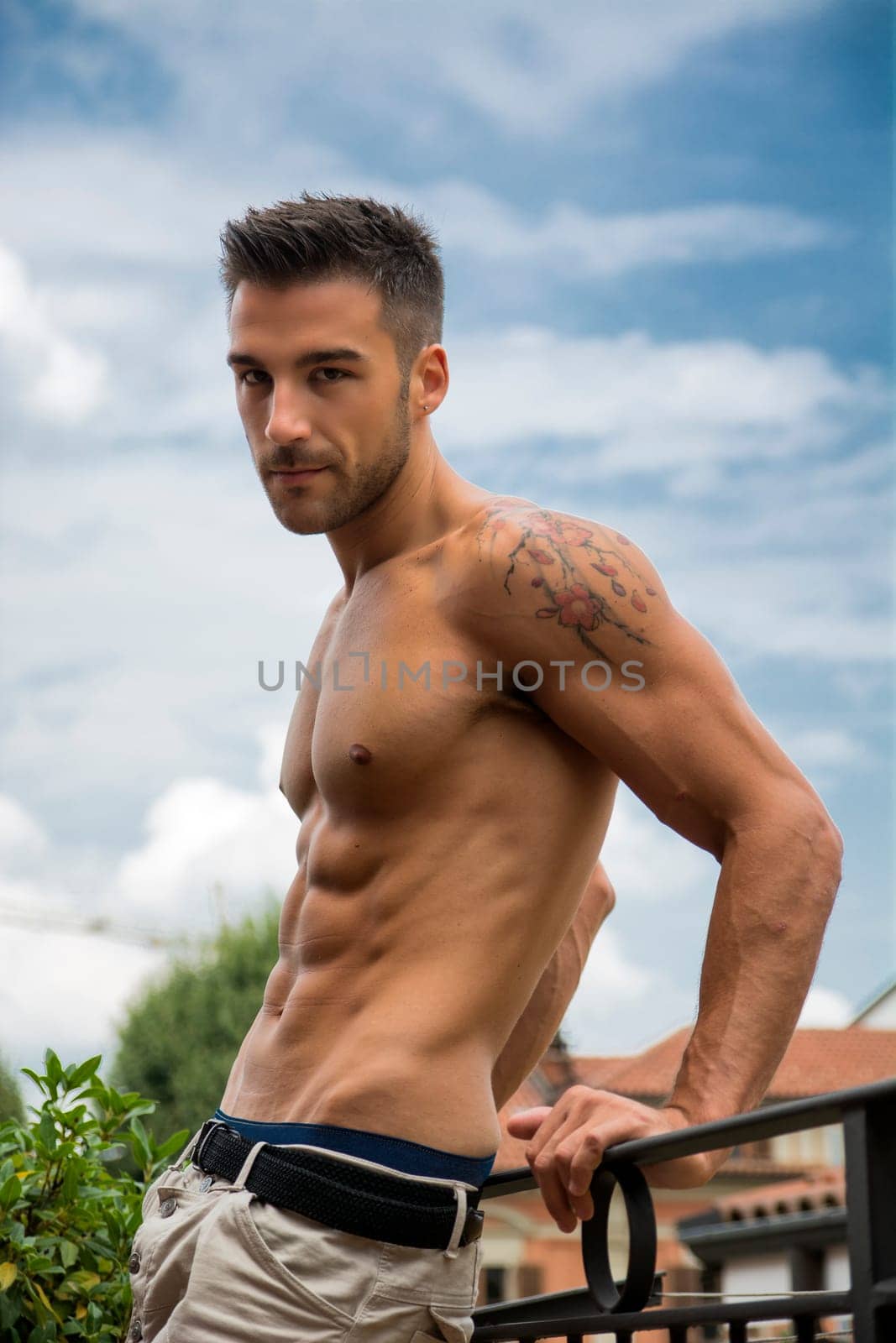 Handsome shirtless muscular young man outdoor, looking at camera