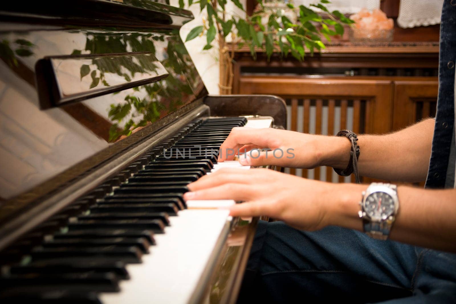 Male hands playing piano indoors inside house