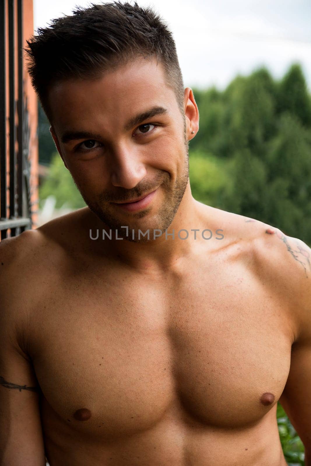 Handsome shirtless young man outdoor, smiling at camera