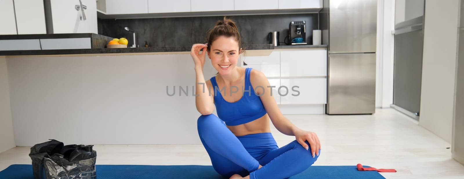 Yoga, welness and wellbeing. Young woman workout, does sport at home, female fitness instructor stretches before exercises on rubber mat in living room by Benzoix