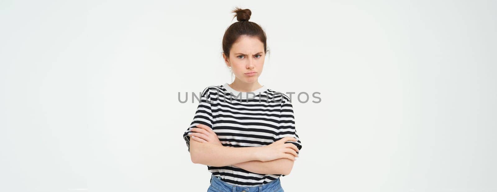 Portrait of angry, offended young woman, cross arms on chest and pouting, looking at camera with insulted face expression, isolated over white background.