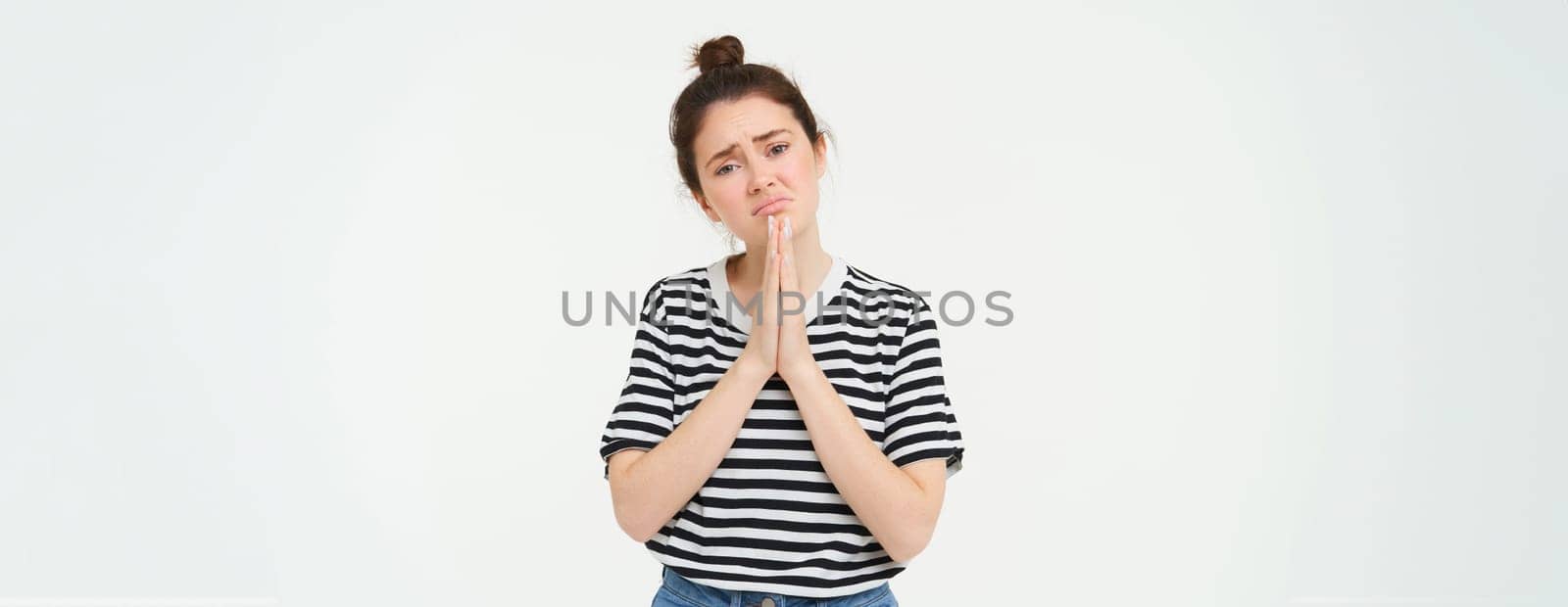 Portrait of sad girl begging you, asking for help, standing in pleading pose, white background. Copy space