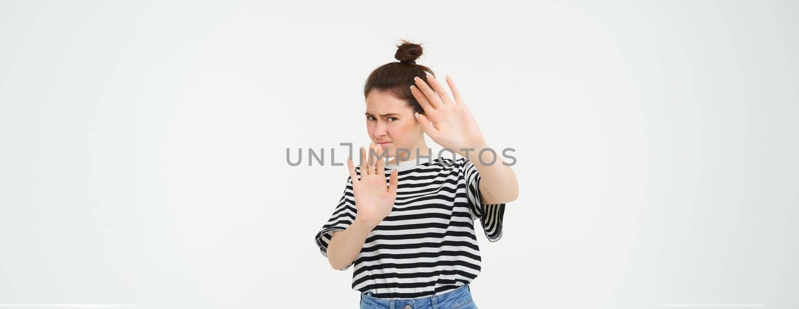 Image of woman refusing something, raising hands in defensive gesture, protecting herself, rejecting offer, declining, standing over white background by Benzoix