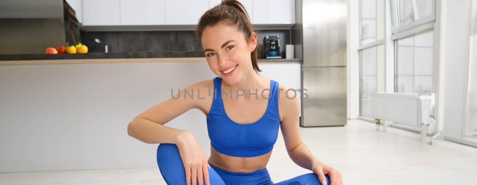 Yoga, welness and wellbeing. Young woman workout, does sport at home, female fitness instructor stretches before exercises on rubber mat in living room by Benzoix