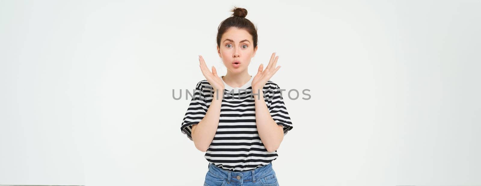 Lifestyle and emotions concept. Portrait of girl with surprised face expression, saying wow, looks impressed at camera, stands over white background.