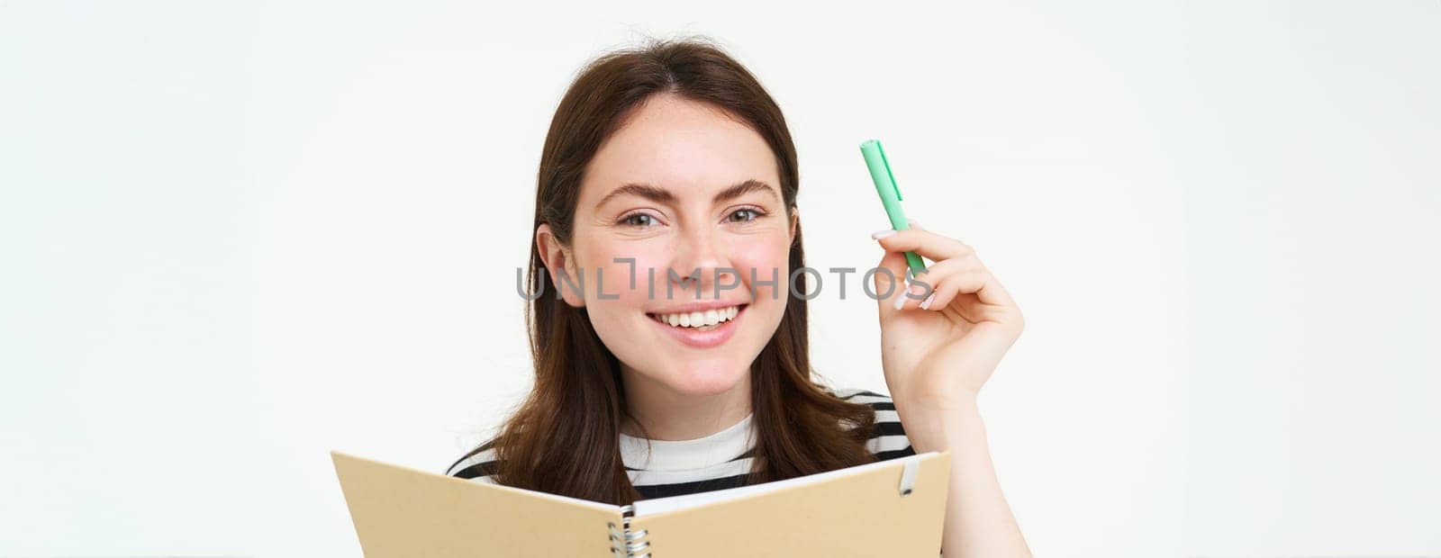 Image of beautiful young woman, student holding notebook, memo planner and pen, smiling and looking happy, isolated against white background.