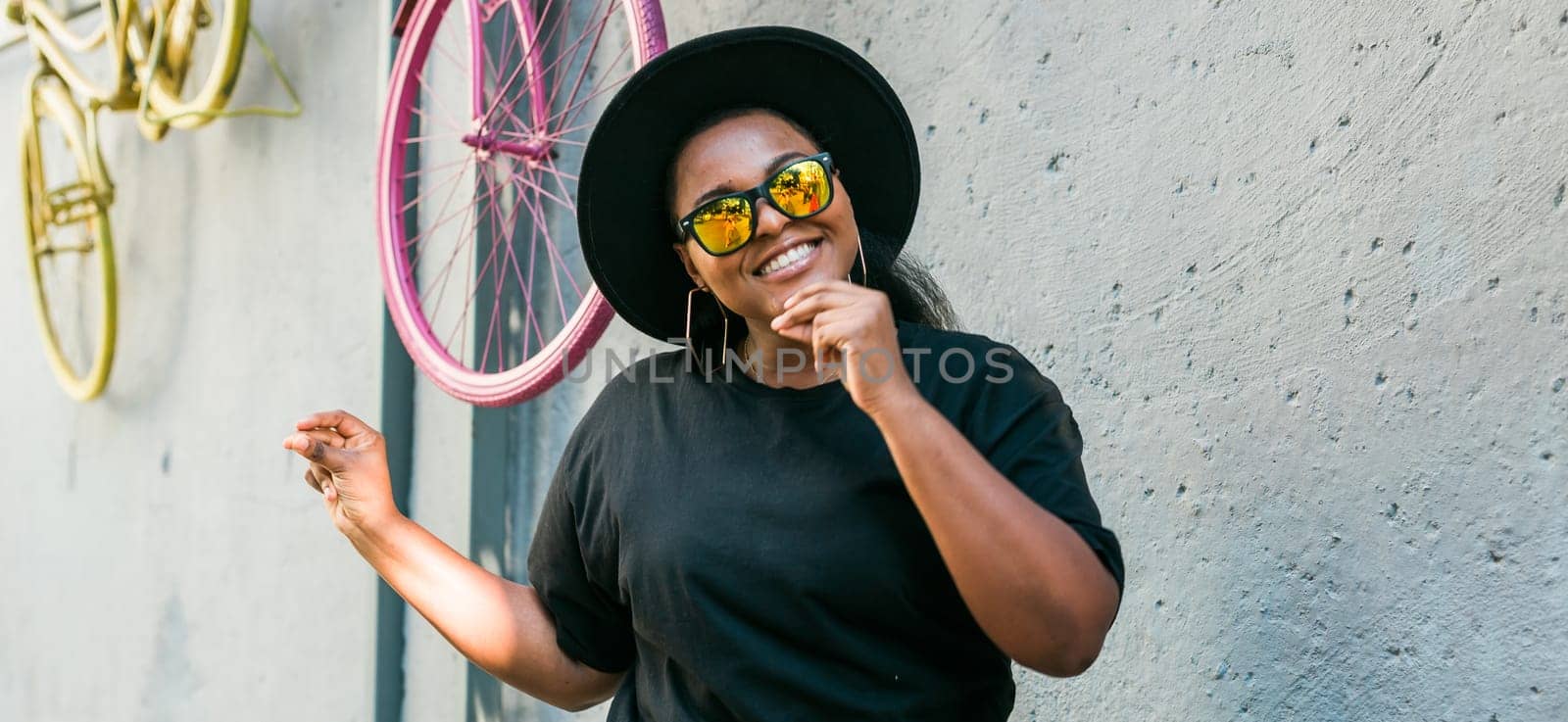 Close-up portrait of stylish young African American girl with curly hair in fashionable round sunglasses. Summer hipster photos with instagram style