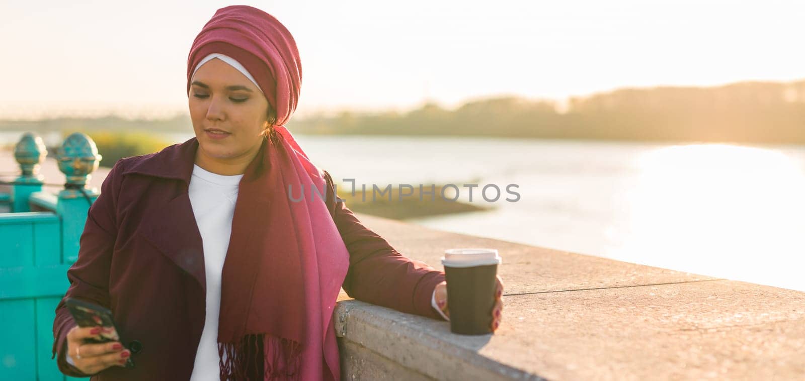 Banner modern arab woman in hijab walking by street and drinking coffee take away in spring time morning copy space by Satura86