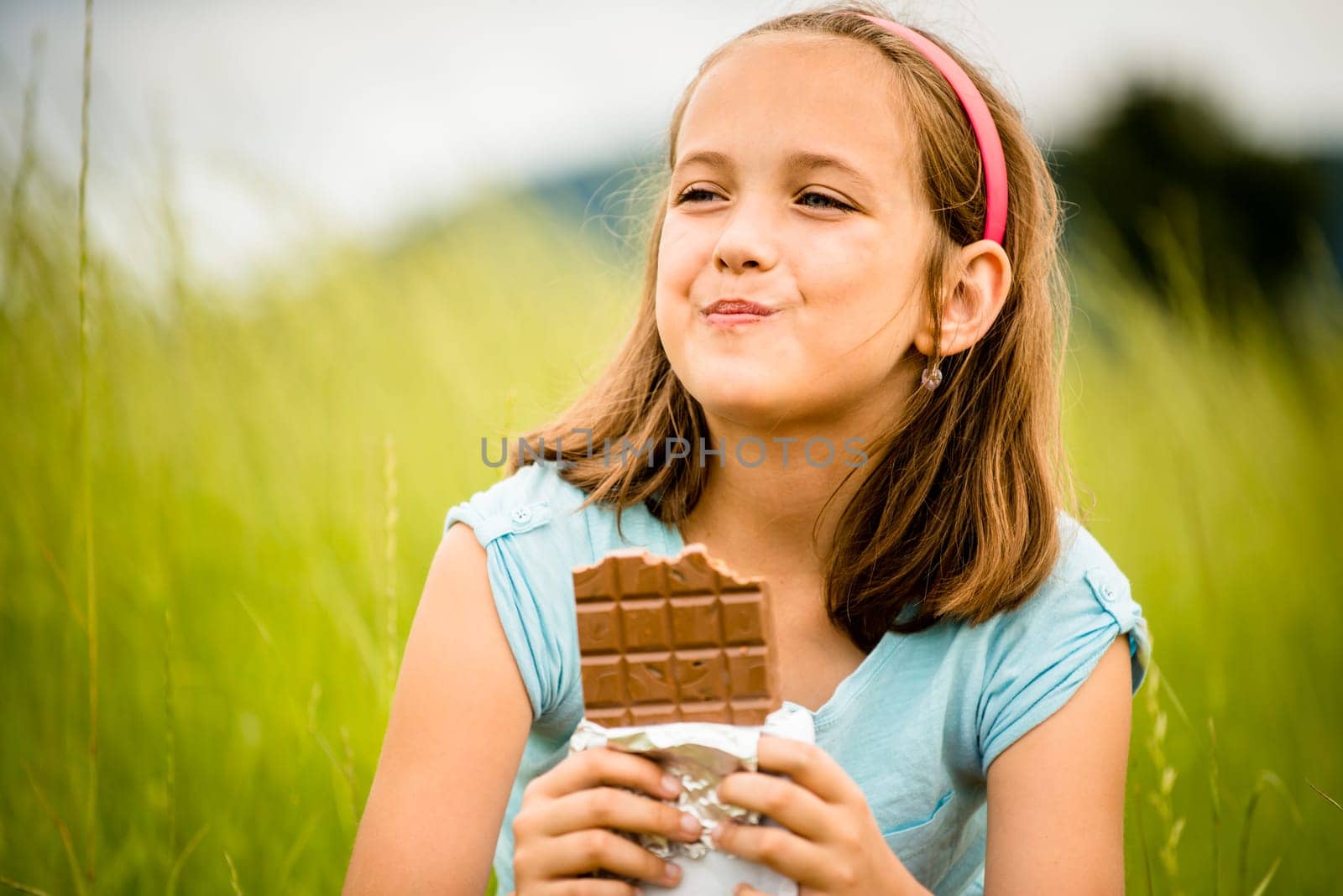 Child eating and relishing chocolate - outdoor in nature