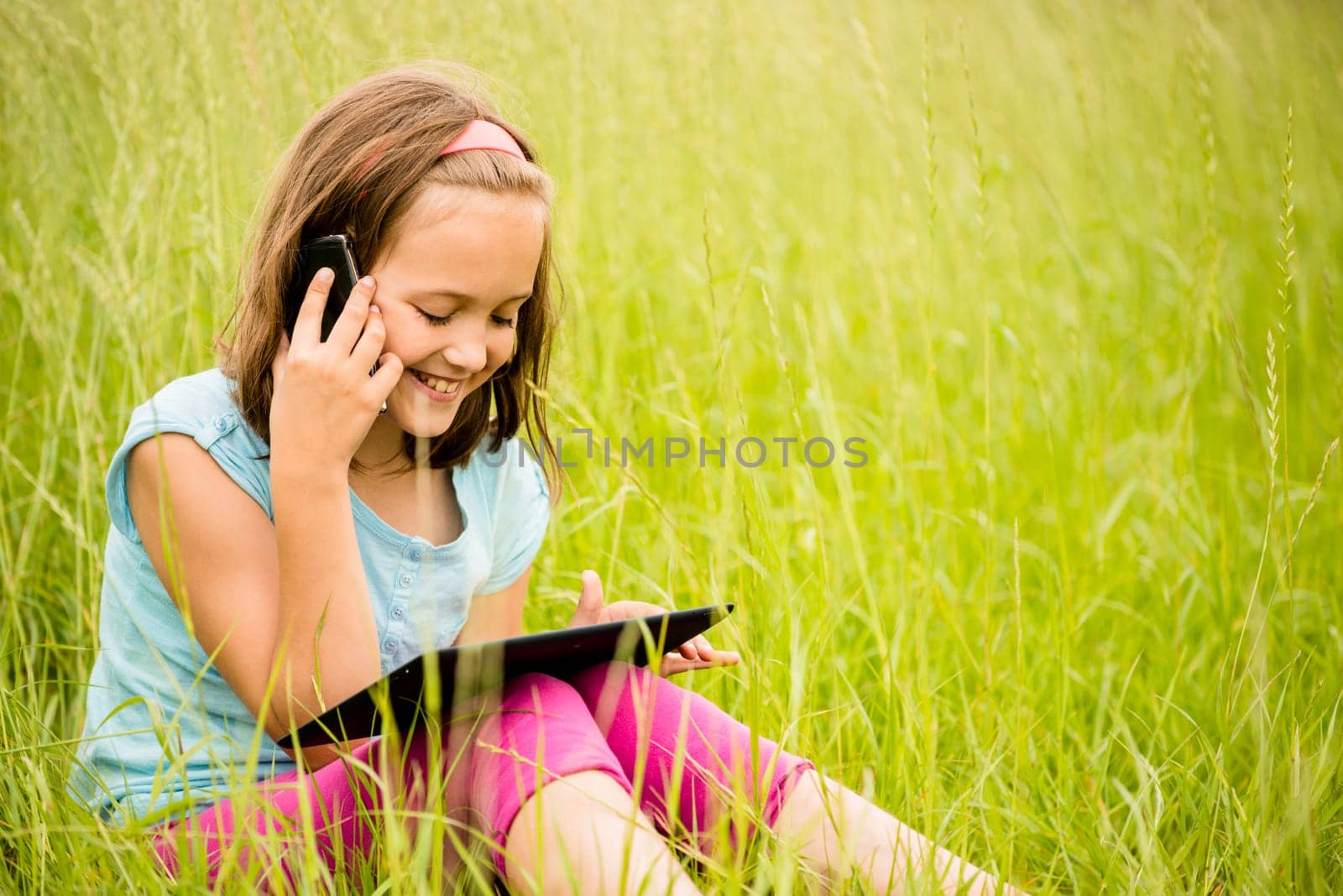 Smiling child watching movie on tablet outdoor in nature