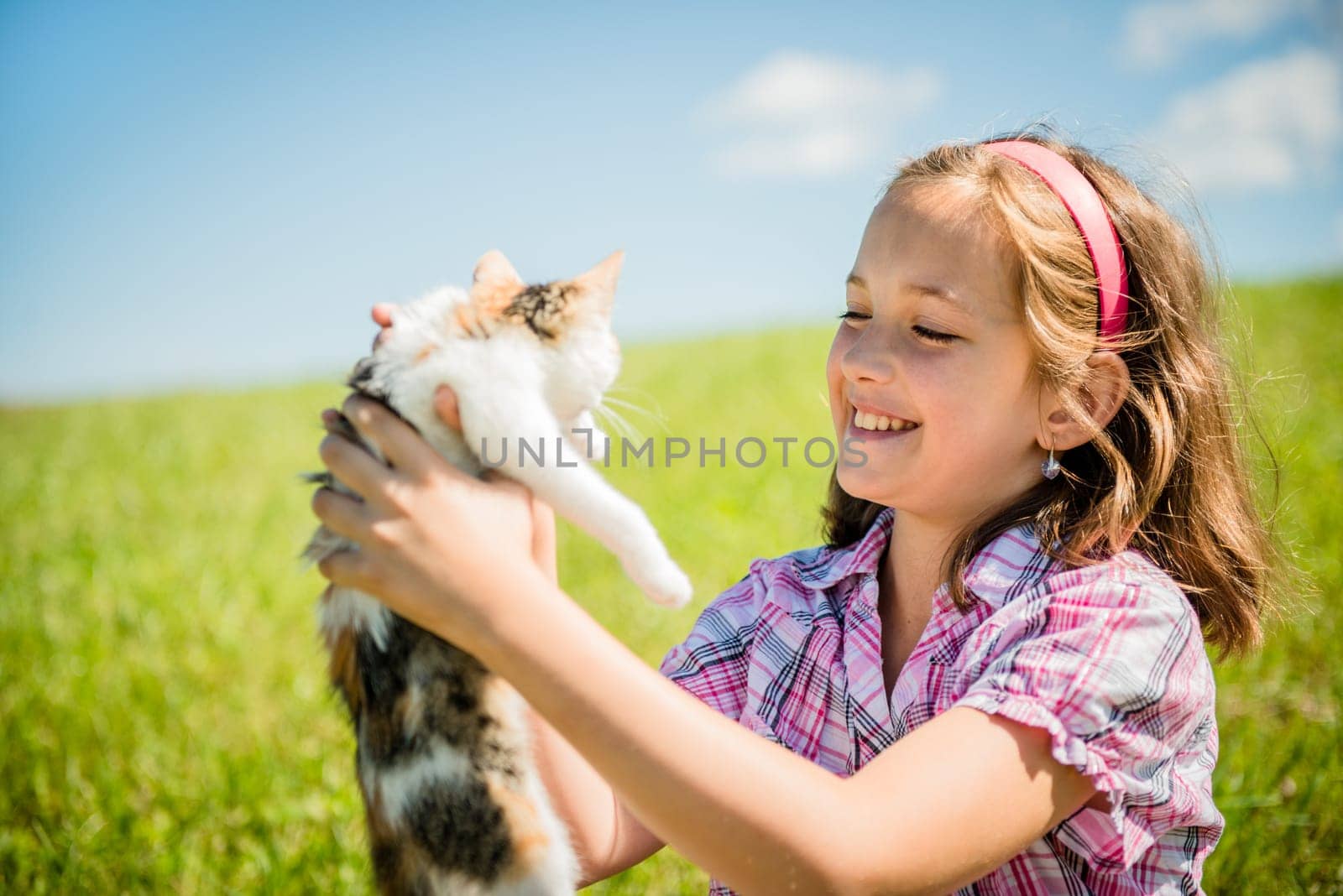 Girl sitting in grass and playing with her small cat