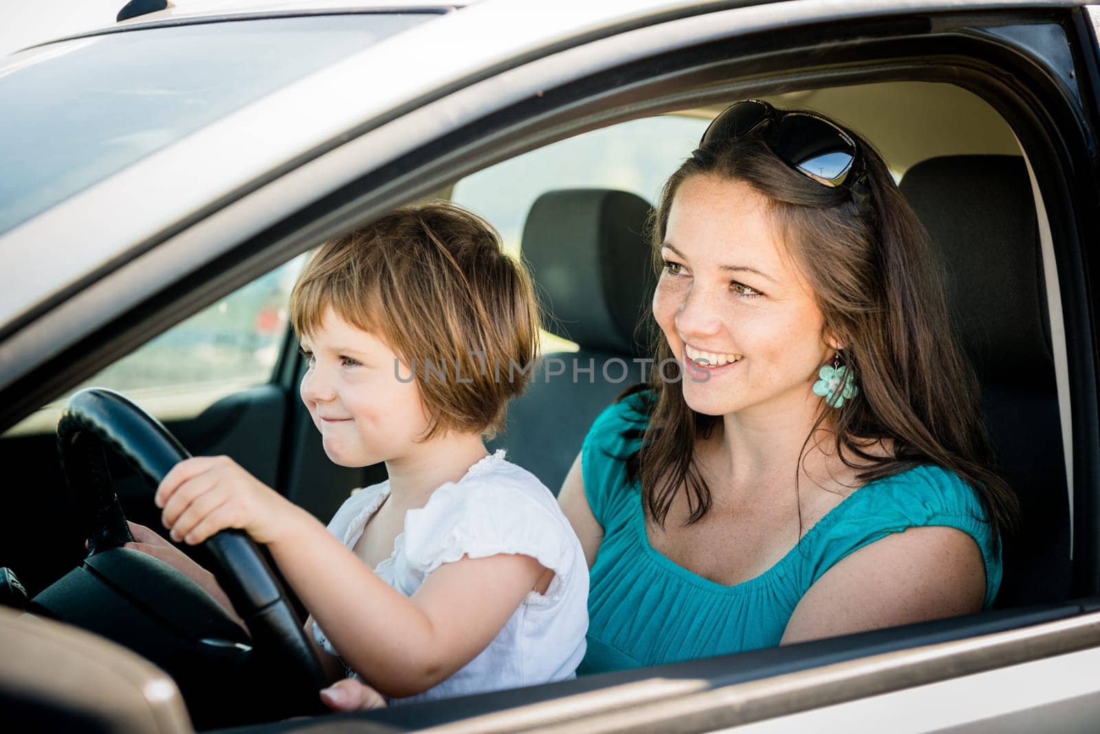 Mother and child pretend driving car sitting both on front driver seat