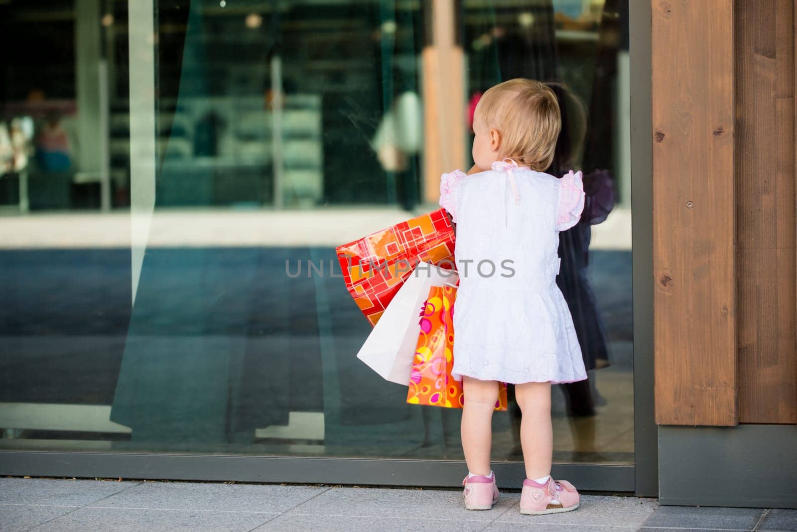 Little girl in white dress looking through shop window