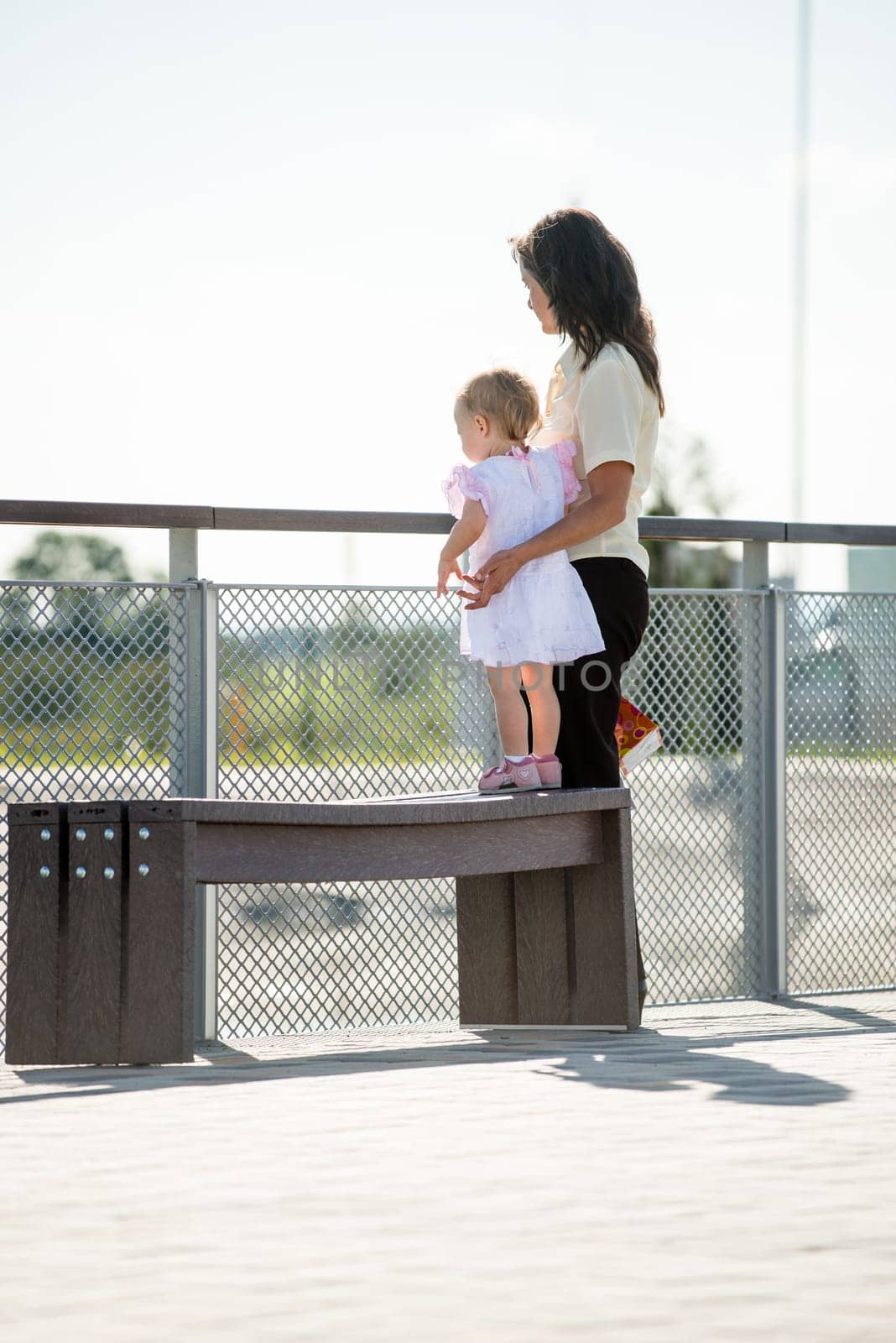 Mother with little girl in white dress looking somewhere to distance